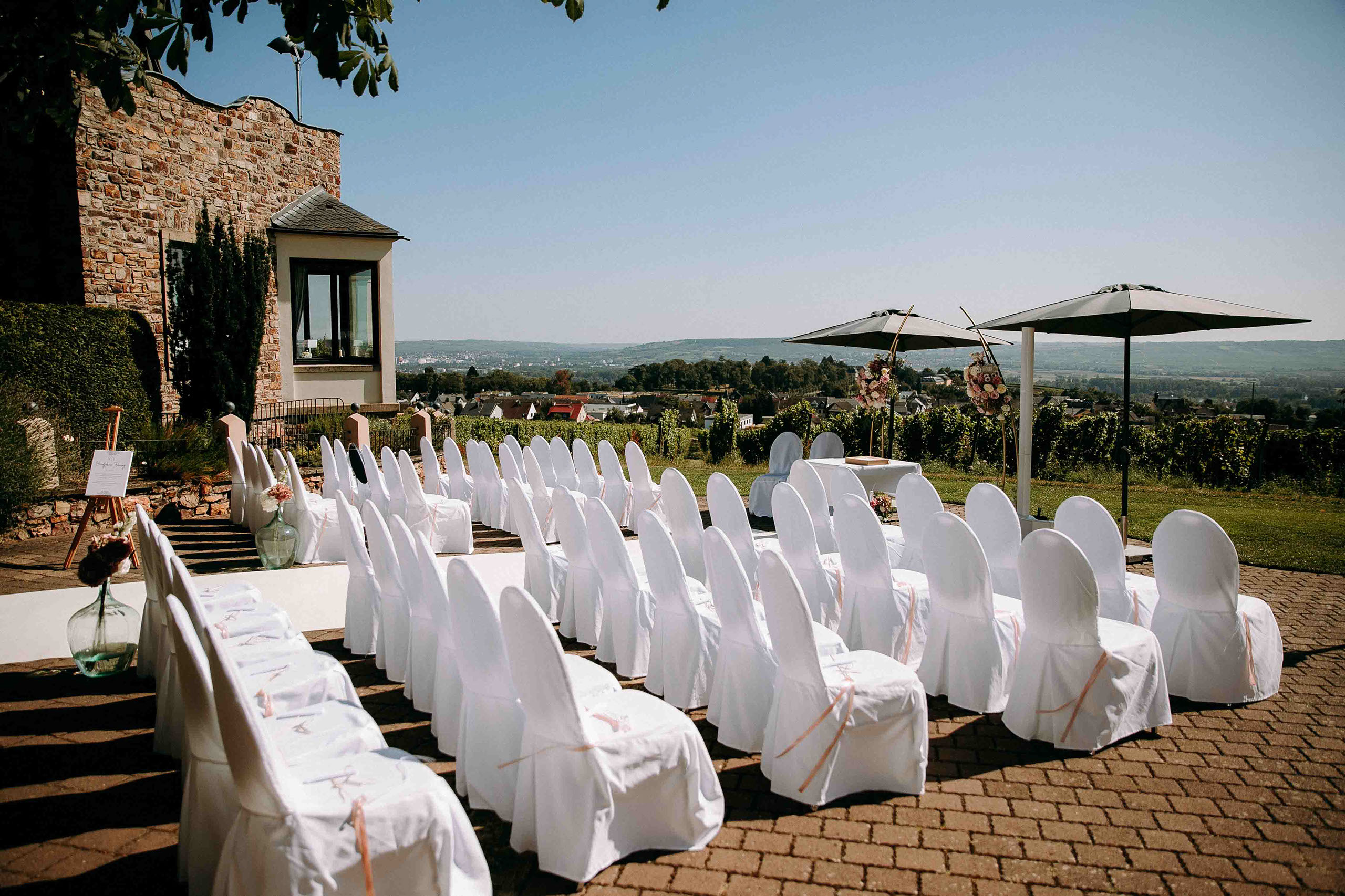 Stilvoll dekorierte Stuhlreihen für eine freie Trauung mit Weitblick auf Burg Schwarzenstein, fotografiert vom Hochzeitsfotograf Rheingau.
