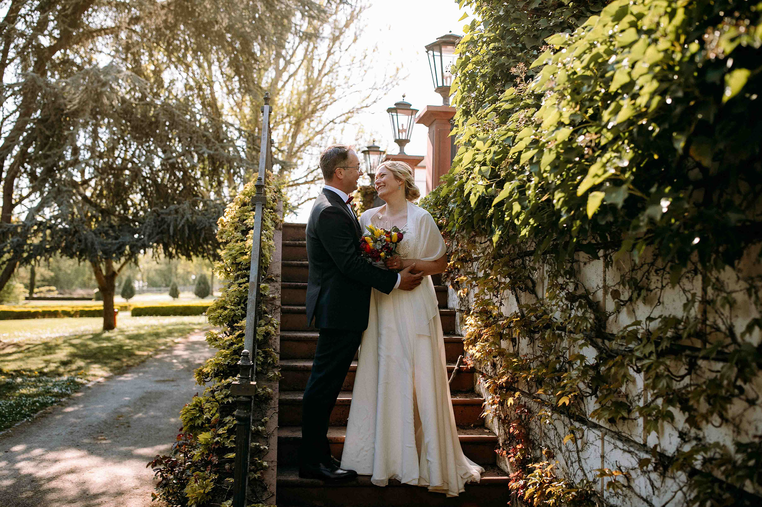 Brautpaar auf einer Treppe im Schloss Reinhartshausen umgeben von grünem Efeu – Hochzeitsfotograf Rheingau