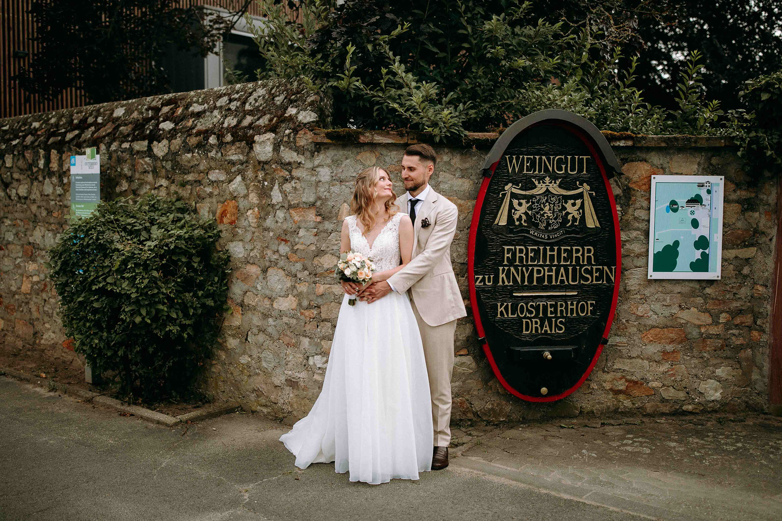 Brautpaar steht verliebt vor dem historischen Weingutschild vom Draiser Hof im Rheingau