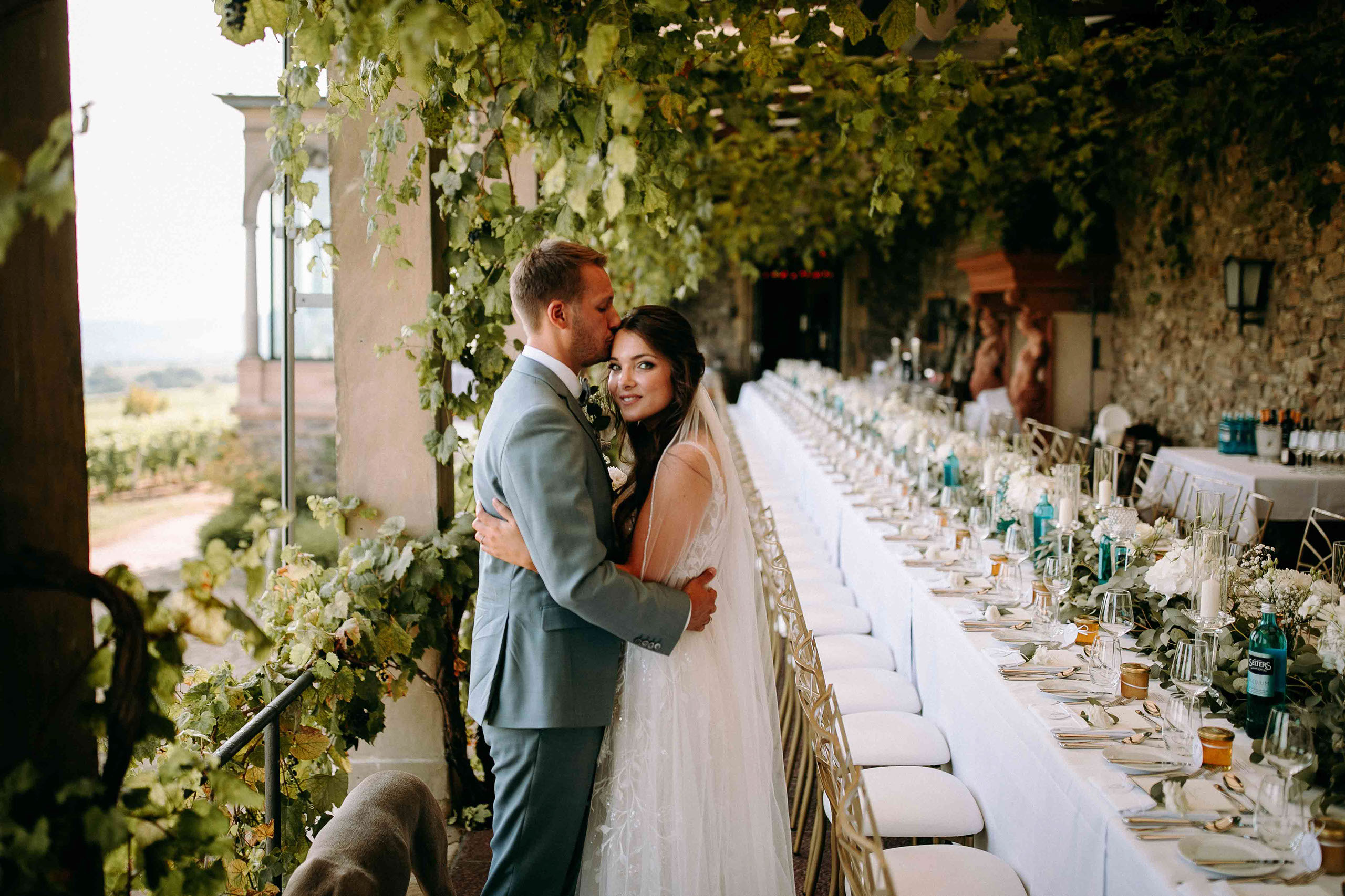 Braut und Bräutigam umarmt vor romantisch dekorierter Tafel auf Burg Schwarzenstein – Hochzeitsfotos Rheingau.
