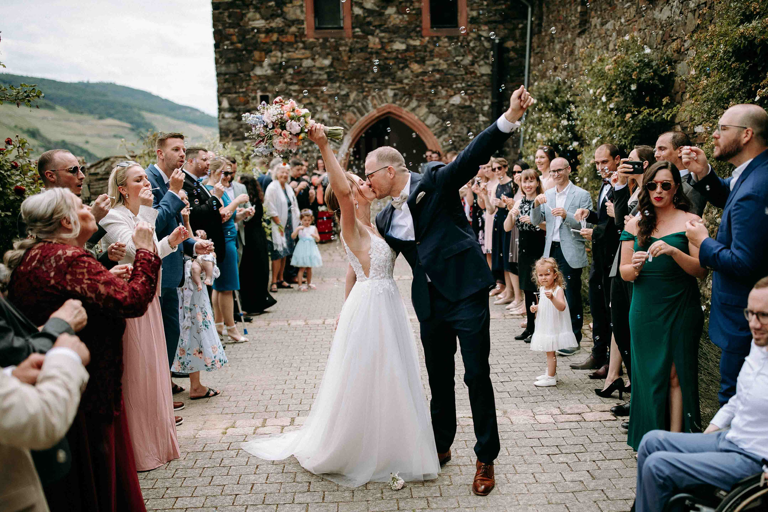 Brautpaar küsst sich unter Seifenblasen bei der Hochzeitsreportage auf der Hochzeitslocation Burg Reichenstein im Rheingau.