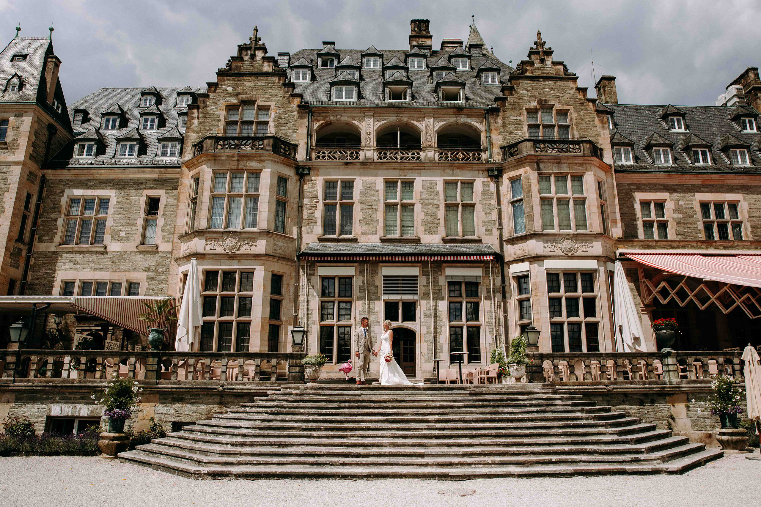 Hochzeitspaar auf der historischen Treppe des Schlosshotels Kronberg – romantische Kulisse.