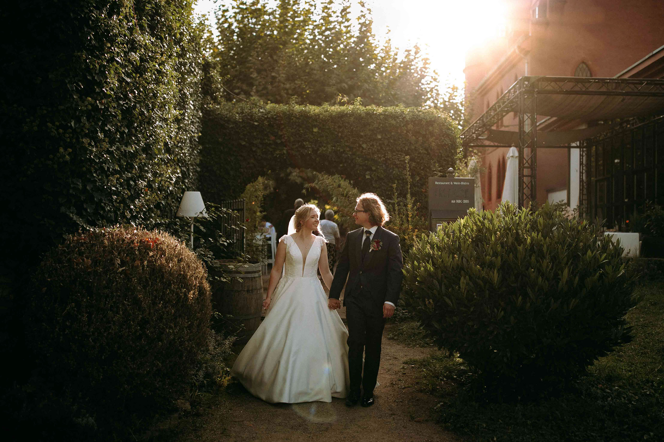 Braut und Bräutigam spazieren durch Garten von Burg Crass – festgehalten vom Hochzeitsfotograf Rheingau.