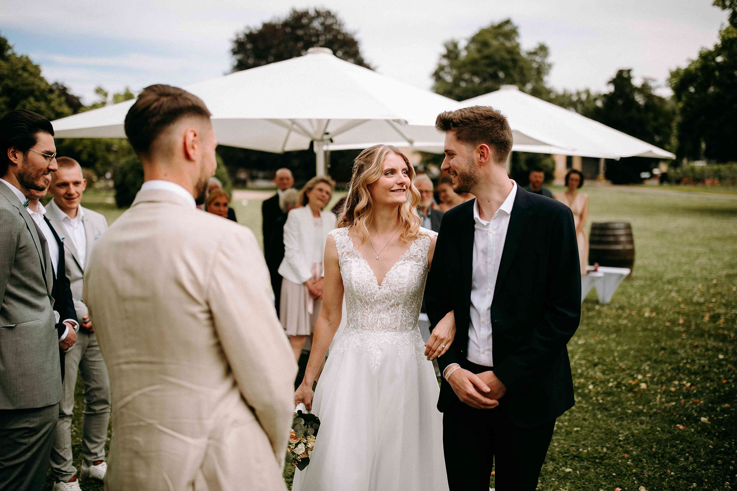 Braut wird von ihrem Bruder zum Bräutigam geführt, Gäste schauen zu