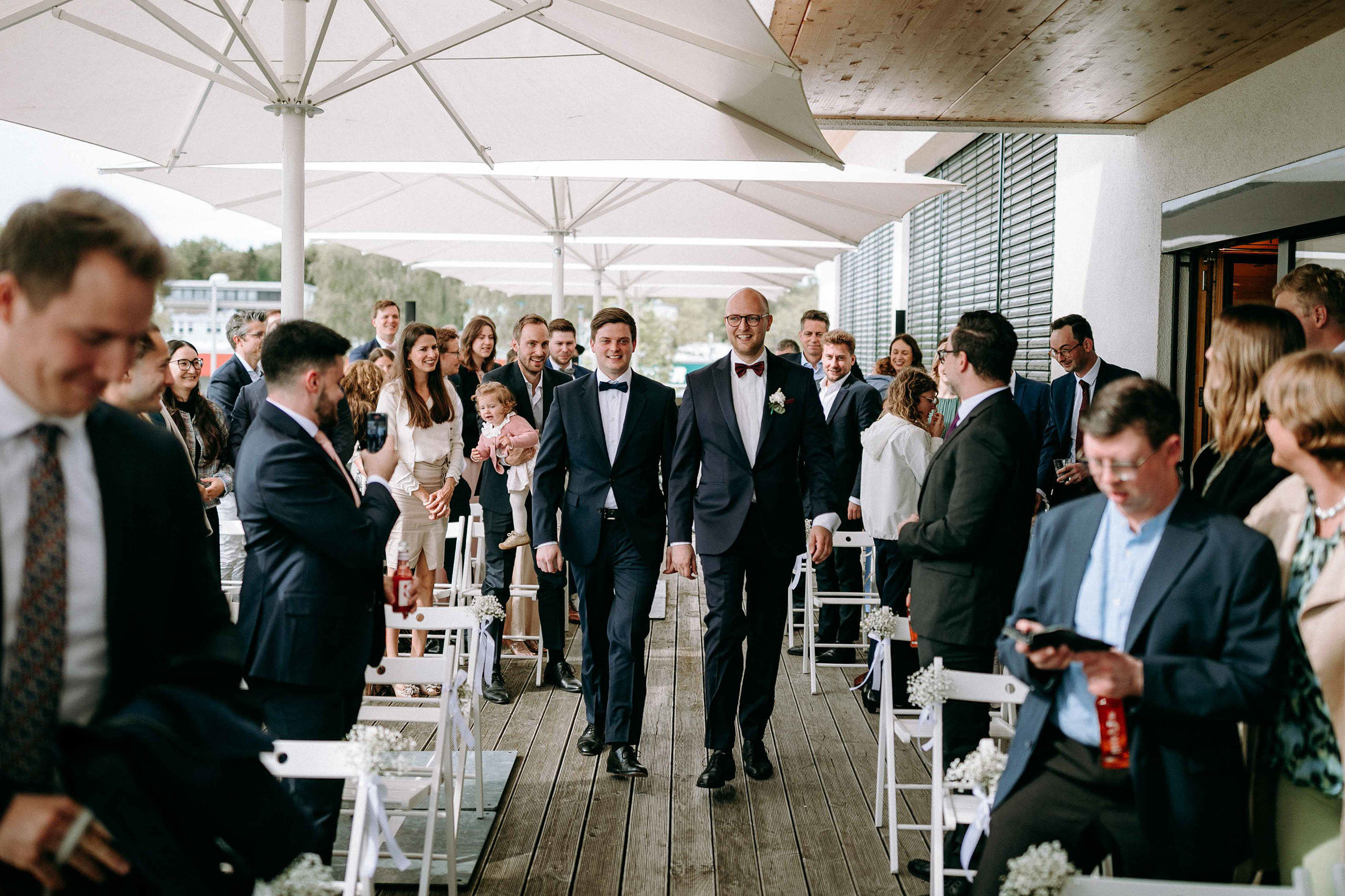 Der Braeutigam laeuft gemeinsam mit seinem Trauzeugen zur Trauzeremonie auf der Dachterrasse ein