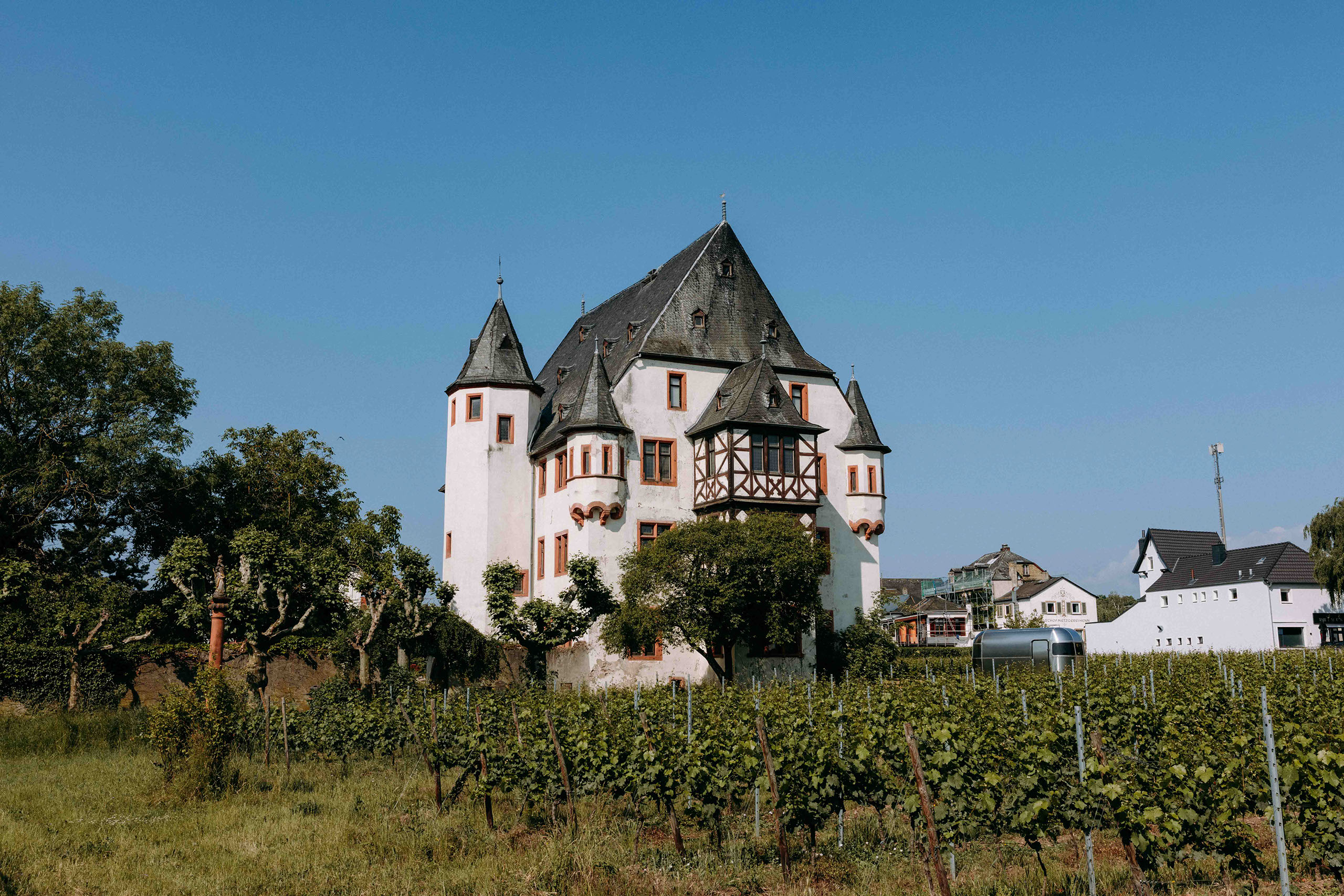 Frontale Ansicht von Schloss Schoenborn mit Türmchen und Fachwerk, umgeben von Weinreben – ideale Hochzeitslocation im Rheingau.