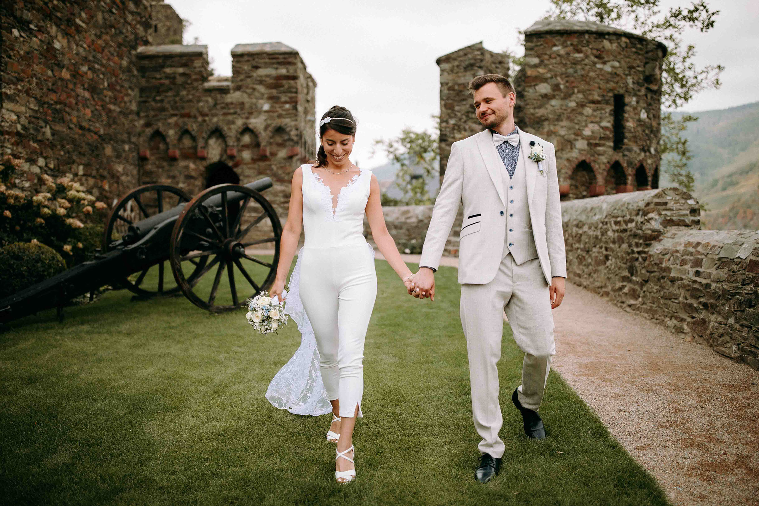 Braut und Bräutigam Hand in Hand im Burggarten der Hochzeitslocation Burg Reichenstein – Hochzeitsfotograf Rheingau.