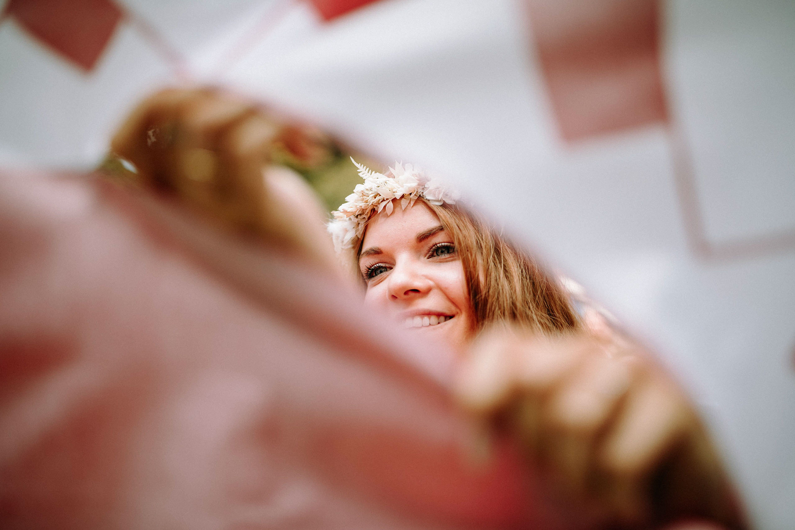 Lächelnde Braut hinter ausgeschnittenem Herz im Laken bei Hochzeit in der Orangerie Bad Homburg.