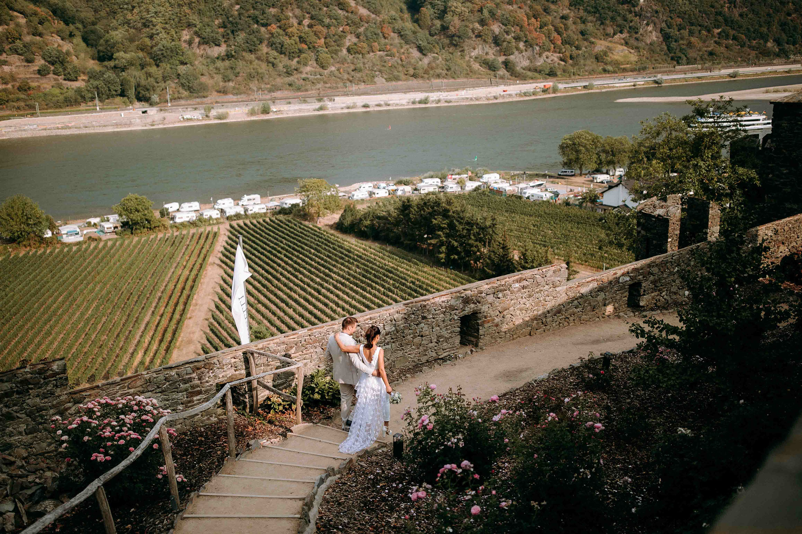 Hochzeitspaar genießt die Aussicht auf Weinberge und den Rhein bei Burg Reichenstein – Hochzeitsfotograf Rheingau