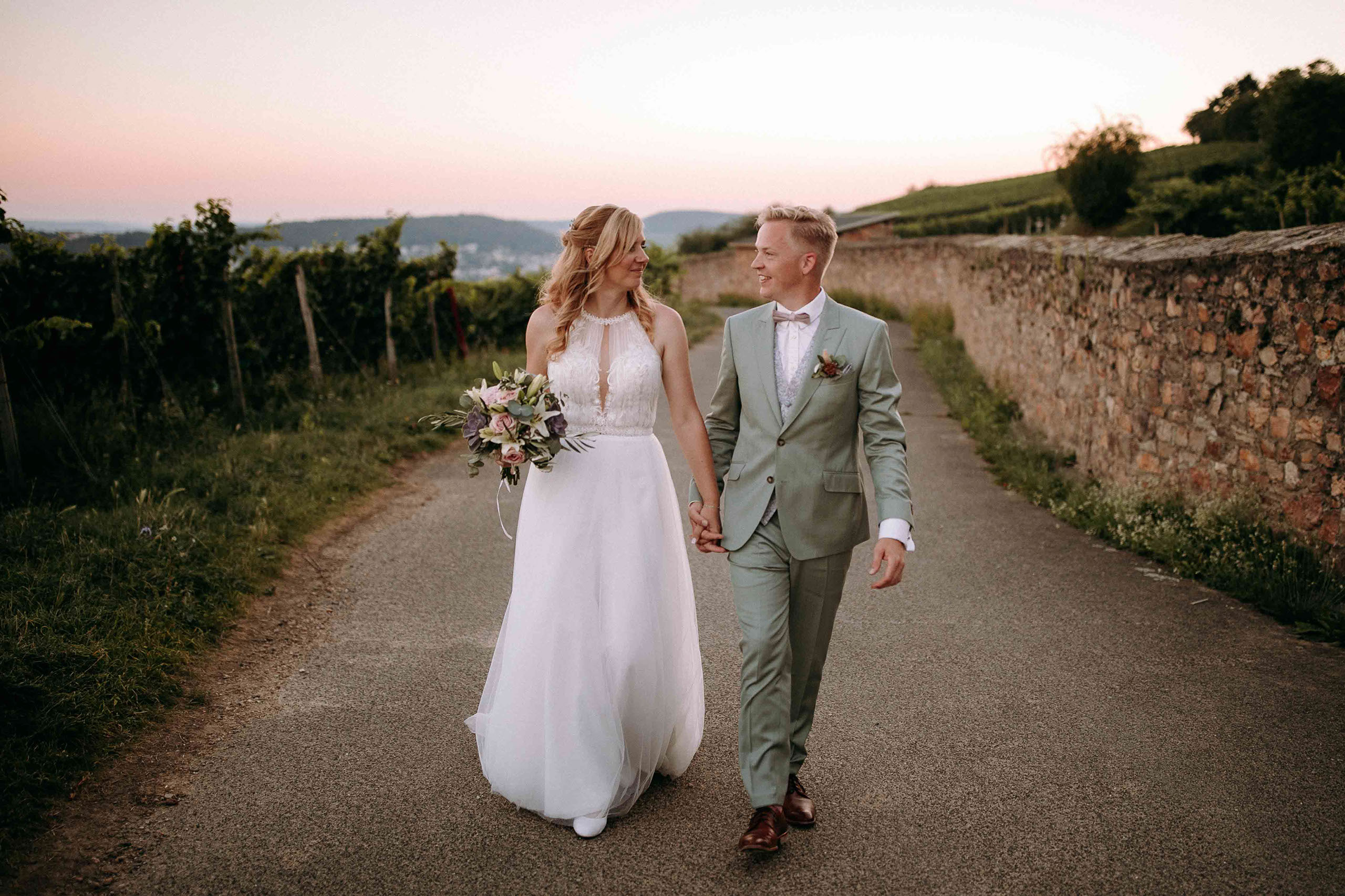Hochzeitspaar spaziert Hand in Hand durch die idyllischen Weinberge des Weinguts Georg Breuer