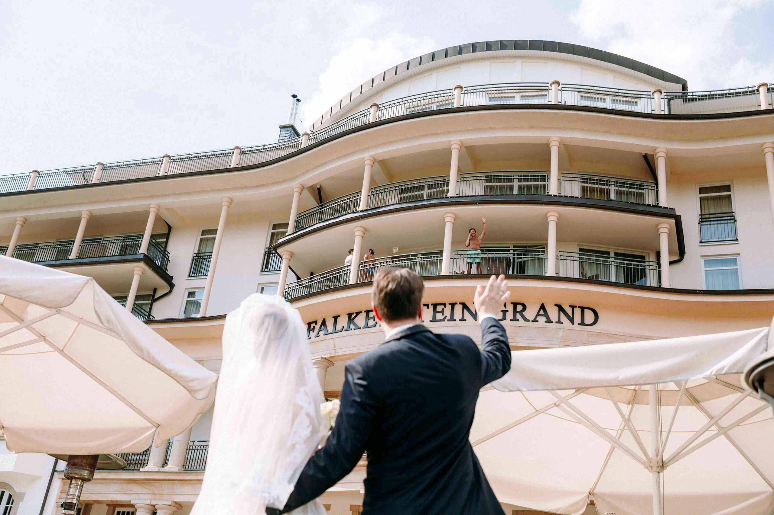 Brautpaar winkt Gästen vor dem Falkenstein Grand Königstein – Hochzeitsfotograf Königstein