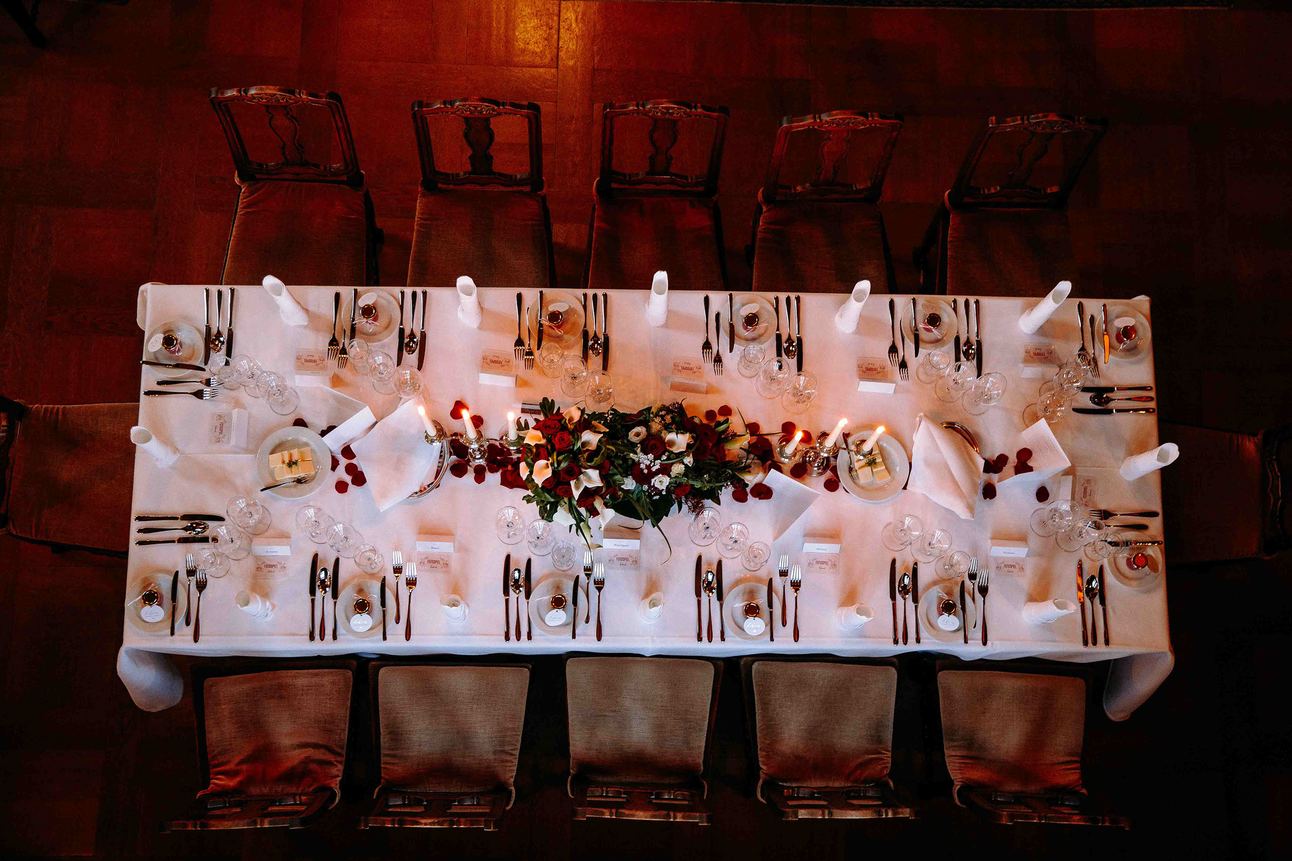 Top-Down-Aufnahme einer stilvoll dekorierten Hochzeitstafel mit rotem Rosen-Schmuck und Kerzen