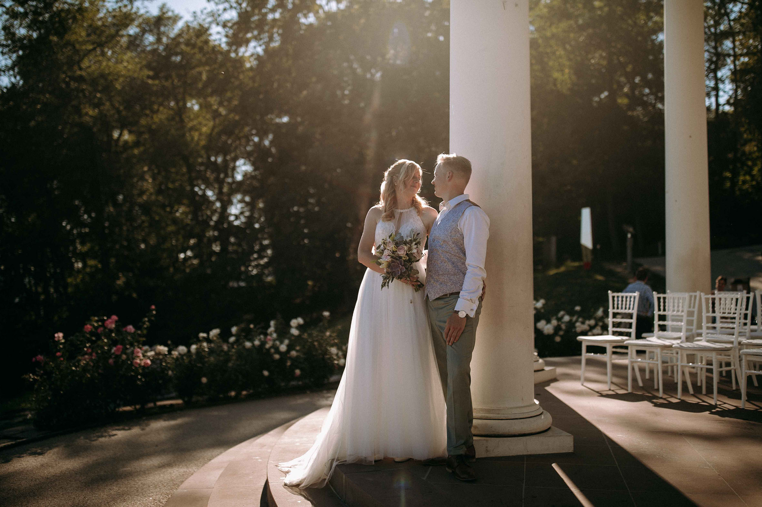 Braut und Bräutigam stehen verliebt unter den Säulen des Niederwaldtempels im Abendlicht.