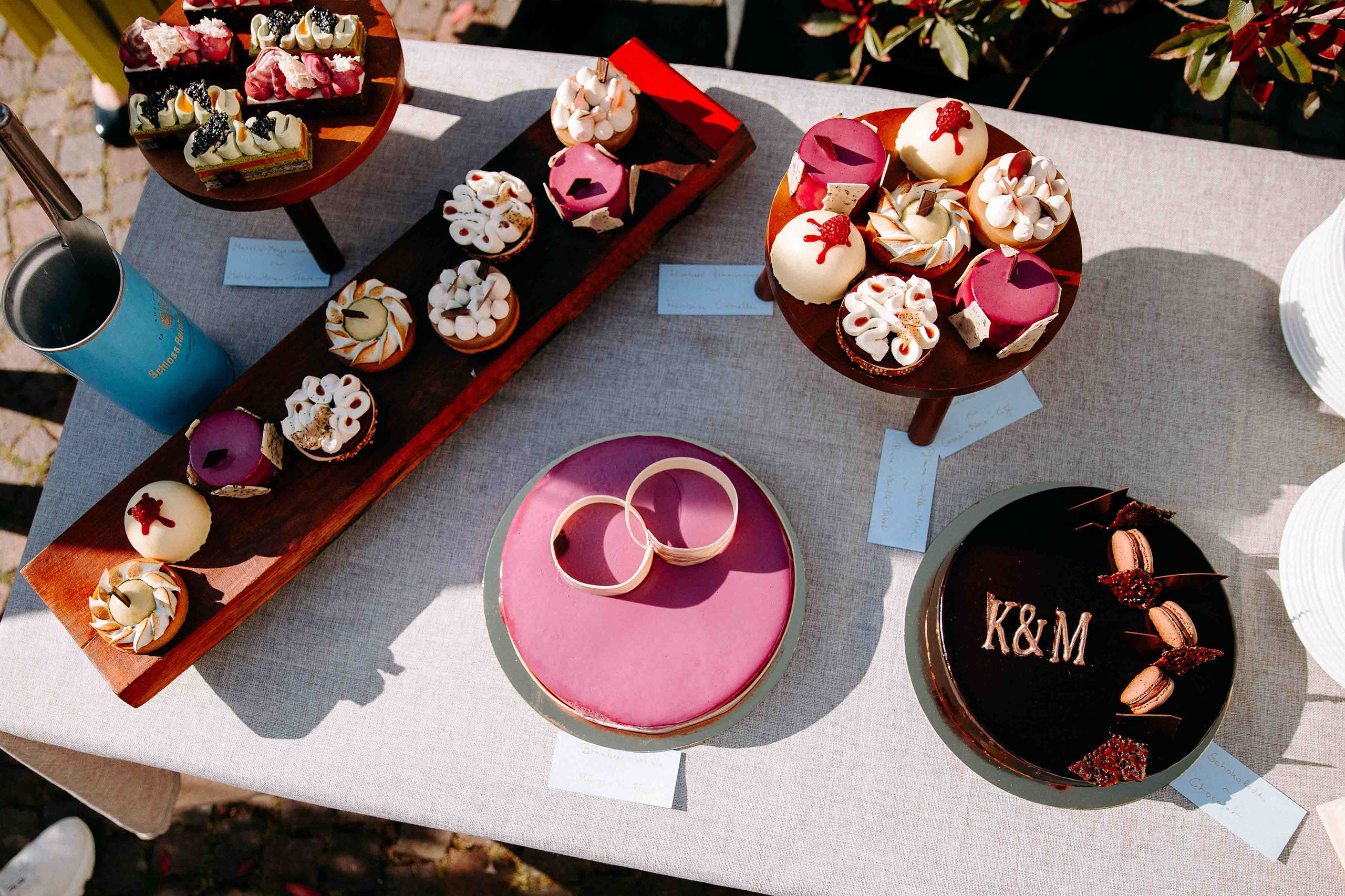 Vogelperspektive auf ein farbenfrohes Tortenbuffet mit kleinen Meisterwerken – festgehalten in der Hochzeitslocation Schloss Reinhartshausen von