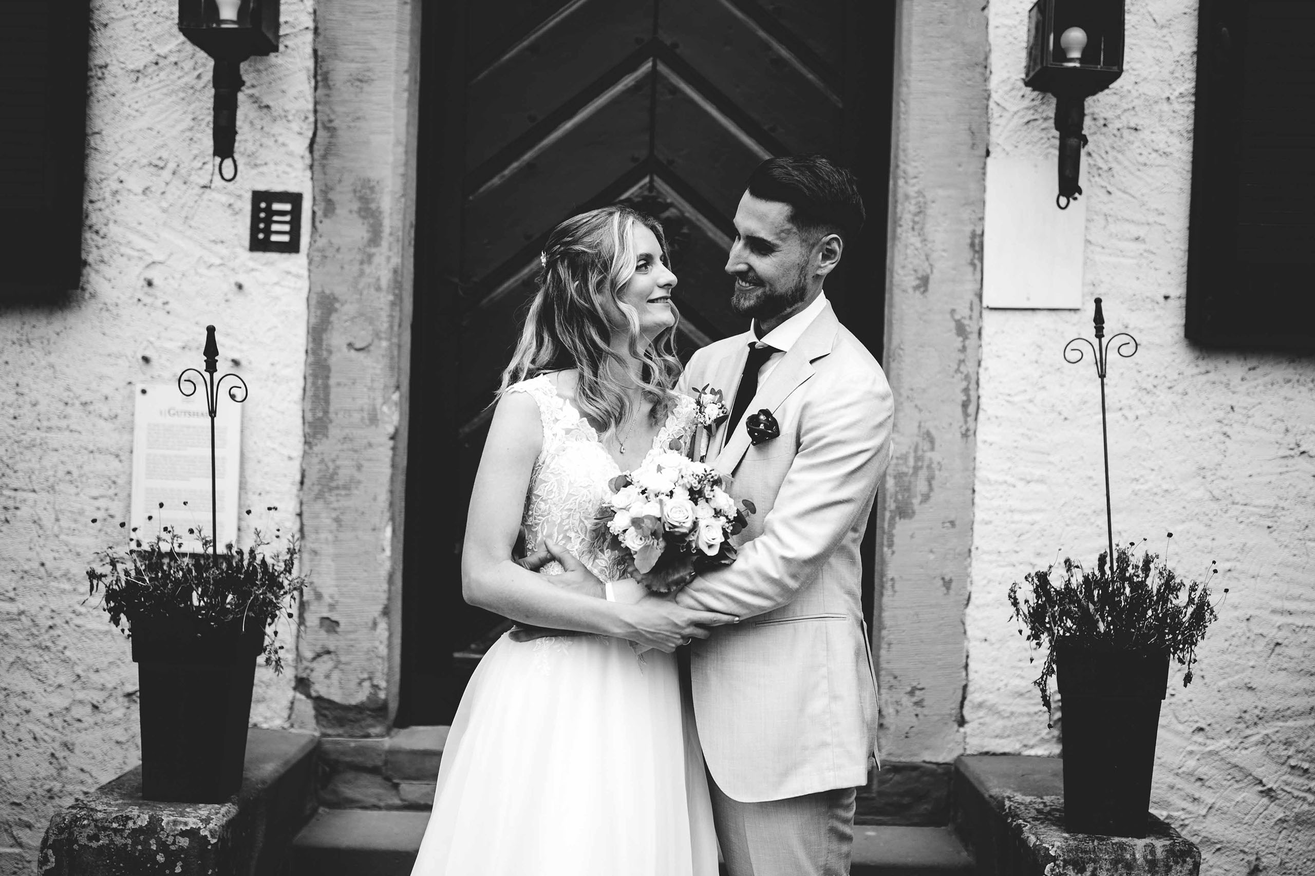 Hochzeitsfoto in Schwarzweiß vor der Tür des Draiser Hofs – Baron Knyphausen als besondere Hochzeitslocation im Rheingau.