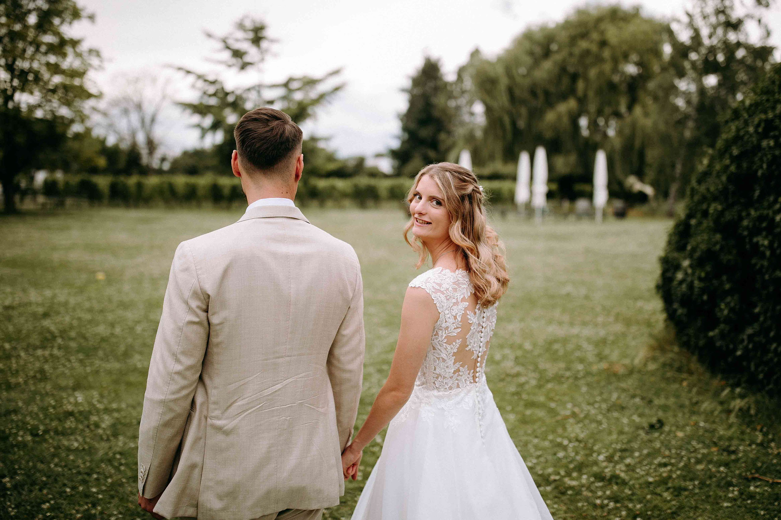 Glückliche Braut blickt zurück im Garten des Draiser Hofs – eingefangen vom Hochzeitsfotograf Rheingau.