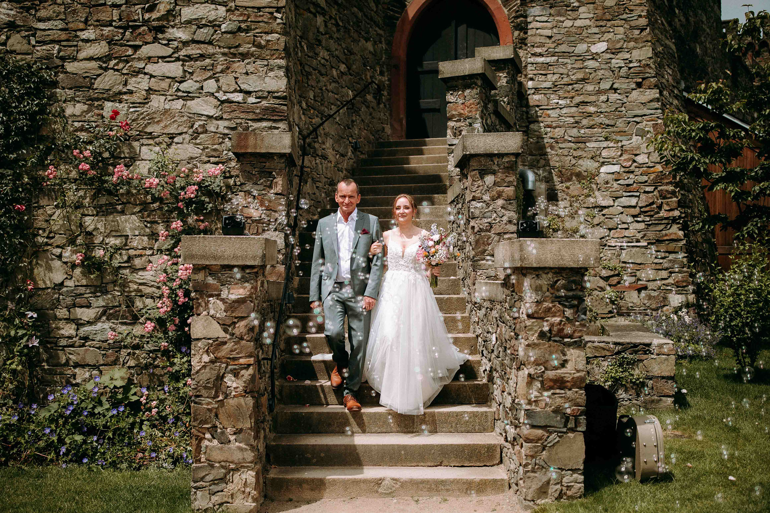 Braut mit Begleitung schreitet feierlich die Burgtreppe hinab bei ihrer Hochzeit auf Burg Reichenstein