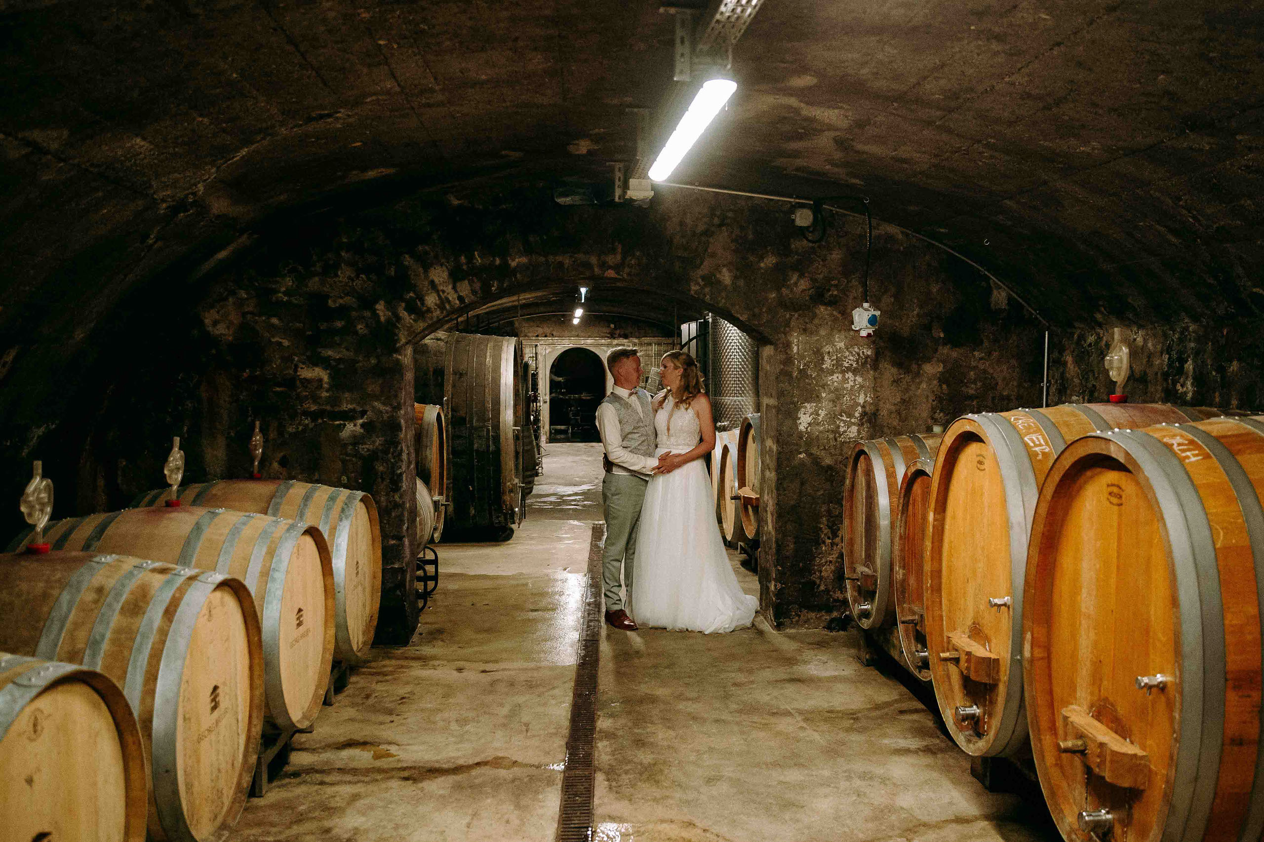Das Brautpaar posiert liebevoll im atmosphärischen Fasskeller des Weinguts Georg Breuer – ein Ort mit Charakter