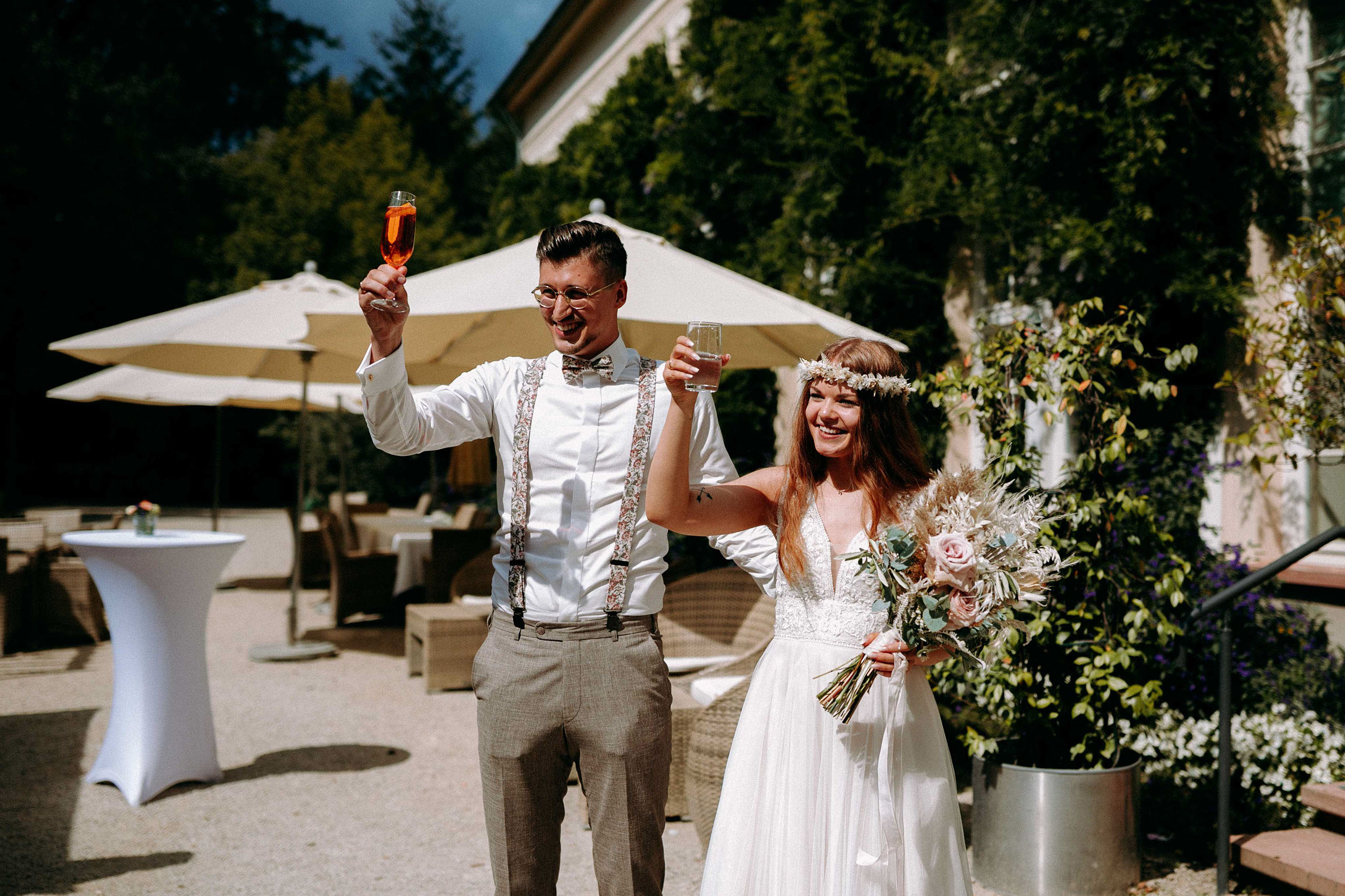 Braut und Bräutigam stoßen mit Gläsern beim Sektempfang in der Orangerie Bad Homburg an.