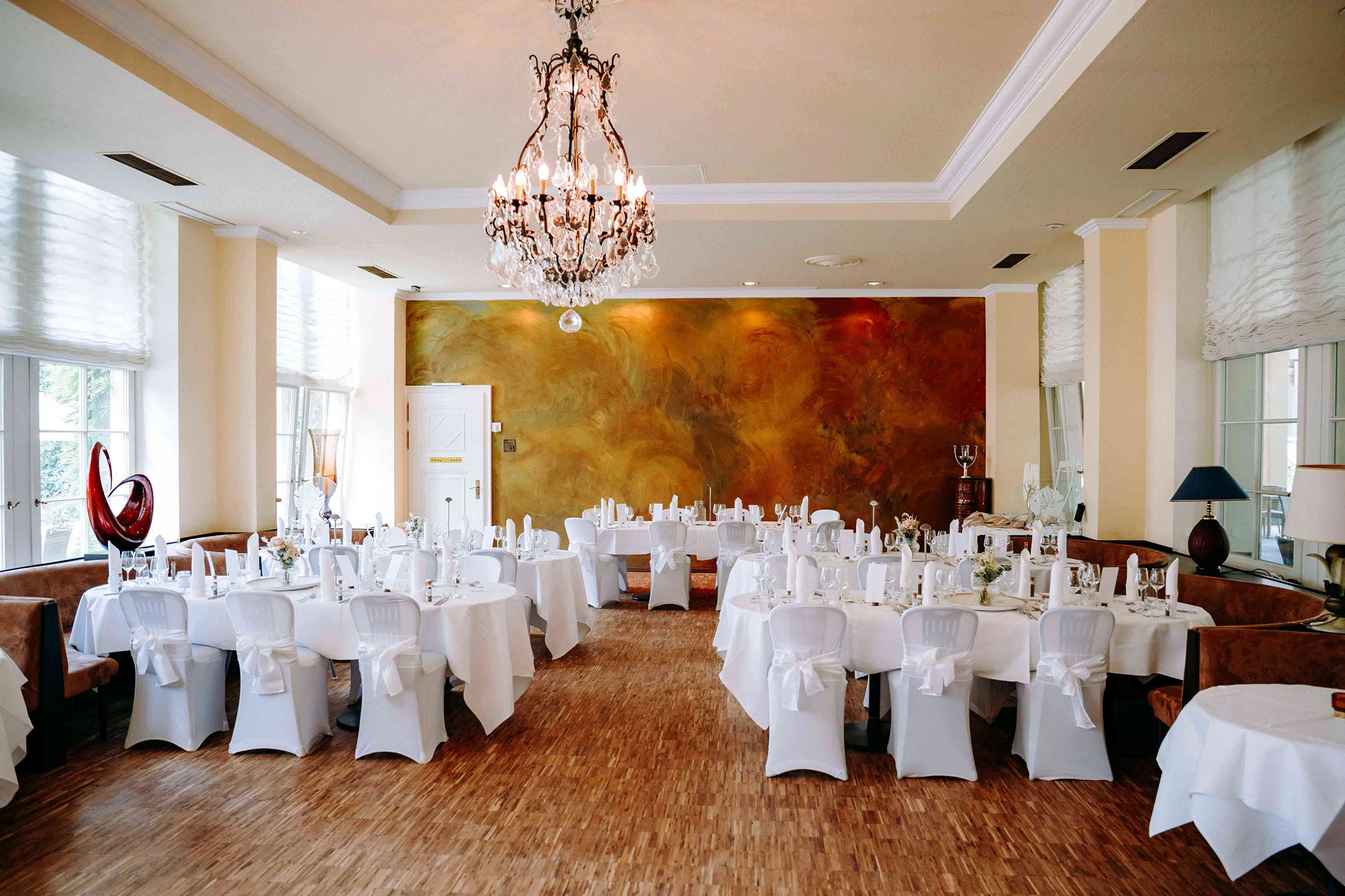 Weiß gedeckte Hochzeitstische mit eleganter Dekoration im Festsaal der Orangerie Bad Homburg.