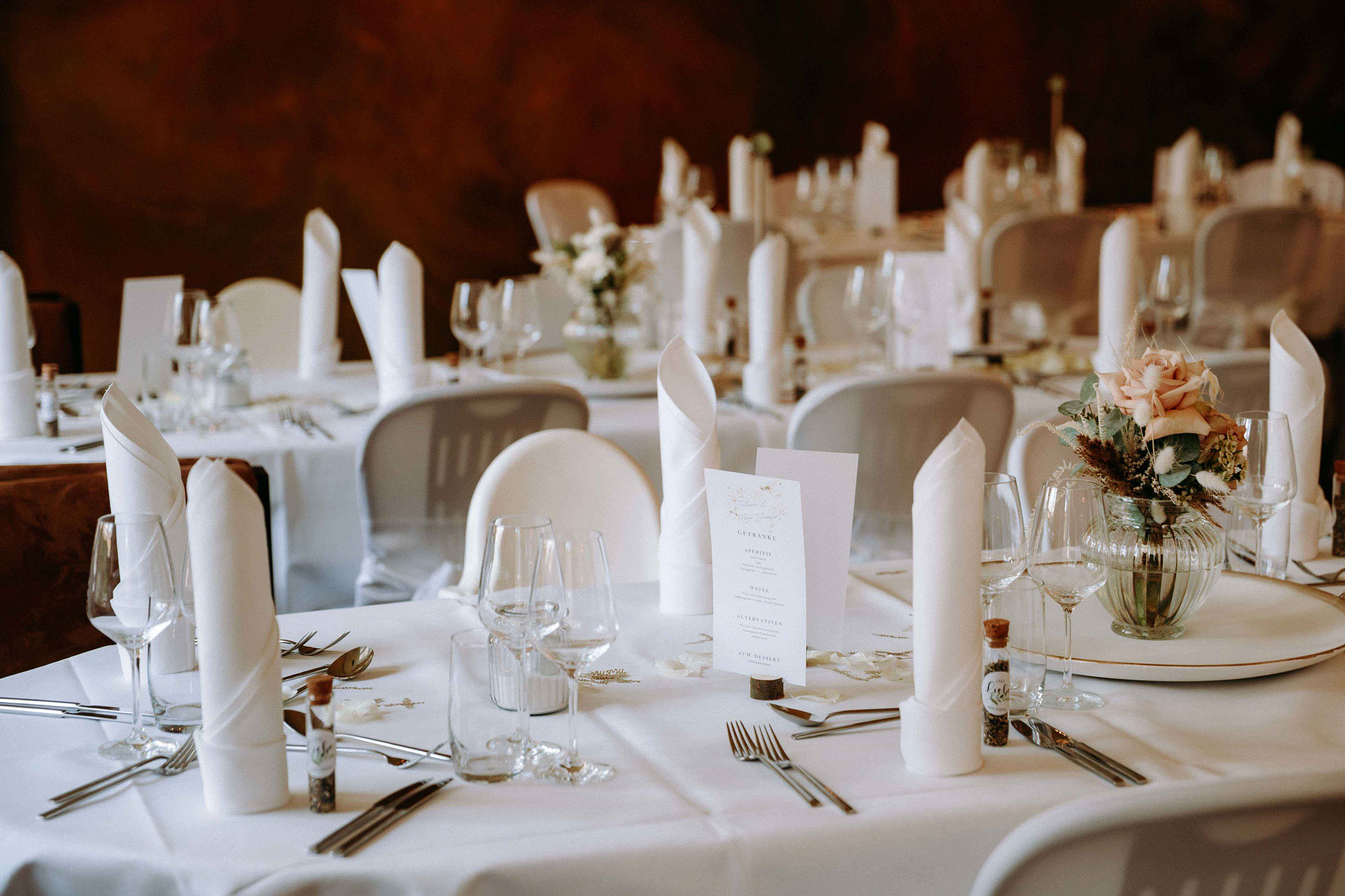 Hochzeitstisch mit Menükarte, Gläsern und romantischer Blumendeko in der Orangerie Bad Homburg.