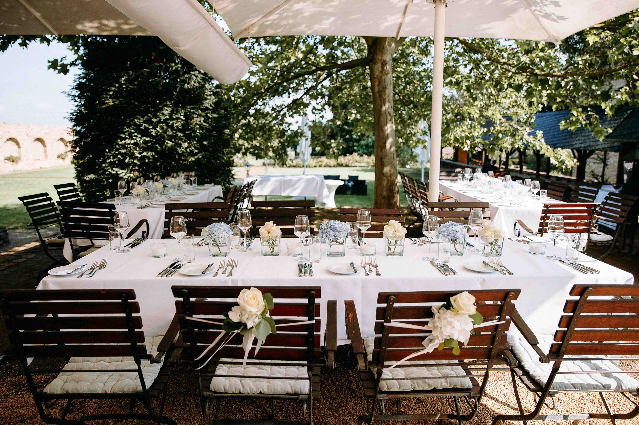 Gedeckte Hochzeitstafeln unter Sonnenschirmen im Garten von Schloss Vollrads