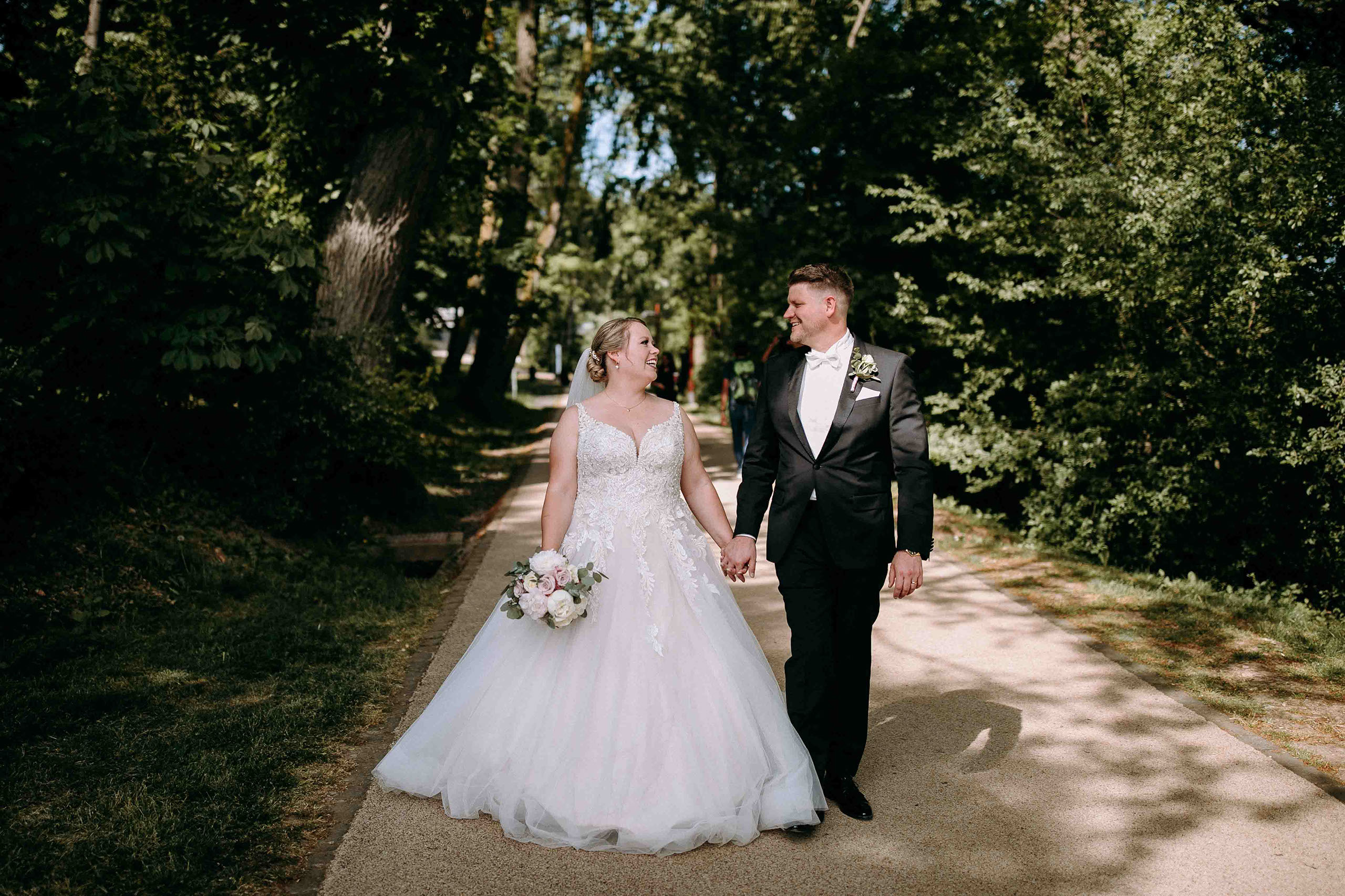 Braut und Bräutigam spazieren Hand in Hand durch den Wald – Hochzeitsfotograf im Rheingau.