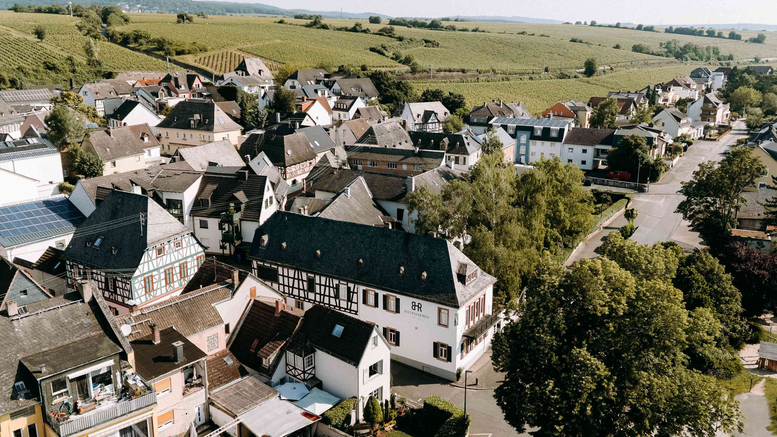 Drohnenaufnahme des Weinguts Balthasar Ress mit umliegenden Altstadthäusern und Weinbergen – malerische Hochzeitskulisse im Rheingau