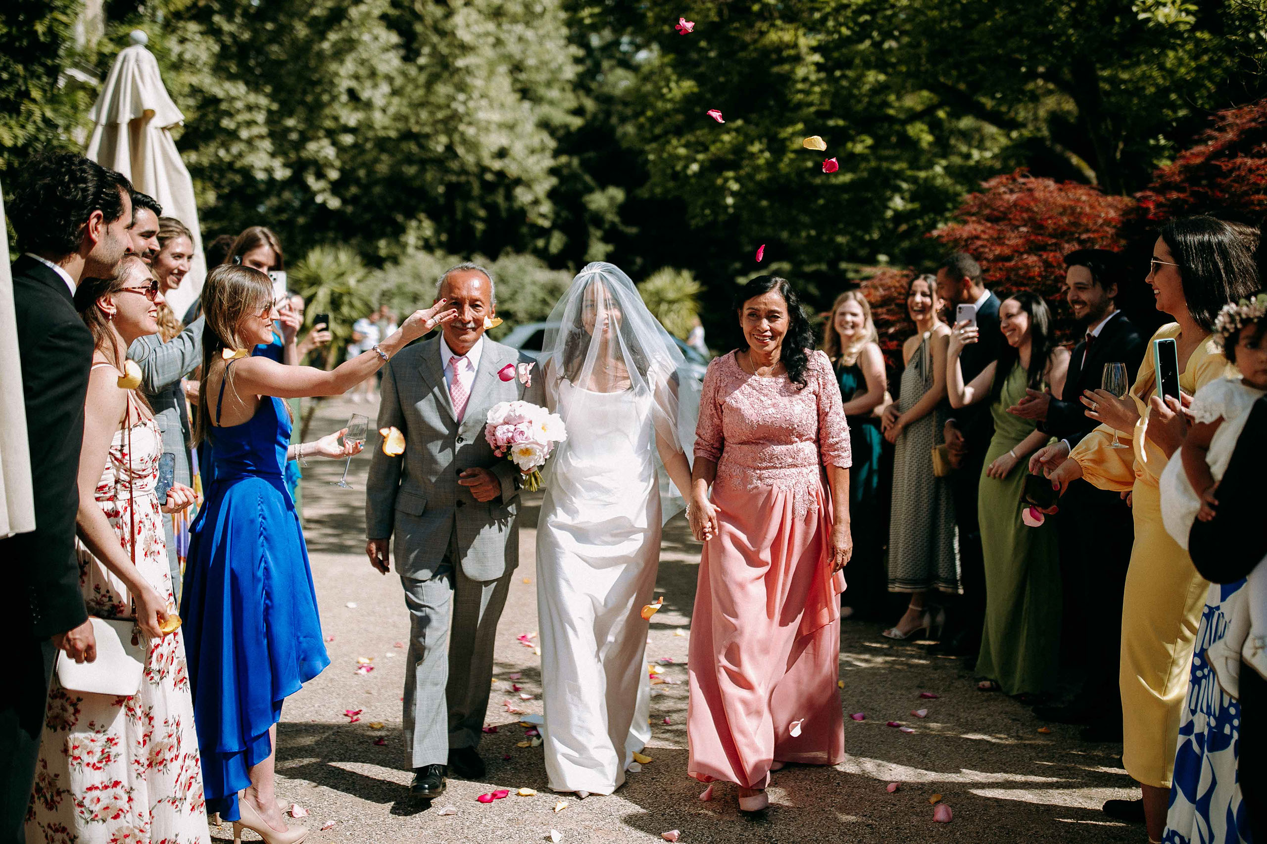 Braut wird von Eltern zur Zeremonie begleitet – Gäste werfen Blüten im Kurpark Bad Homburg.