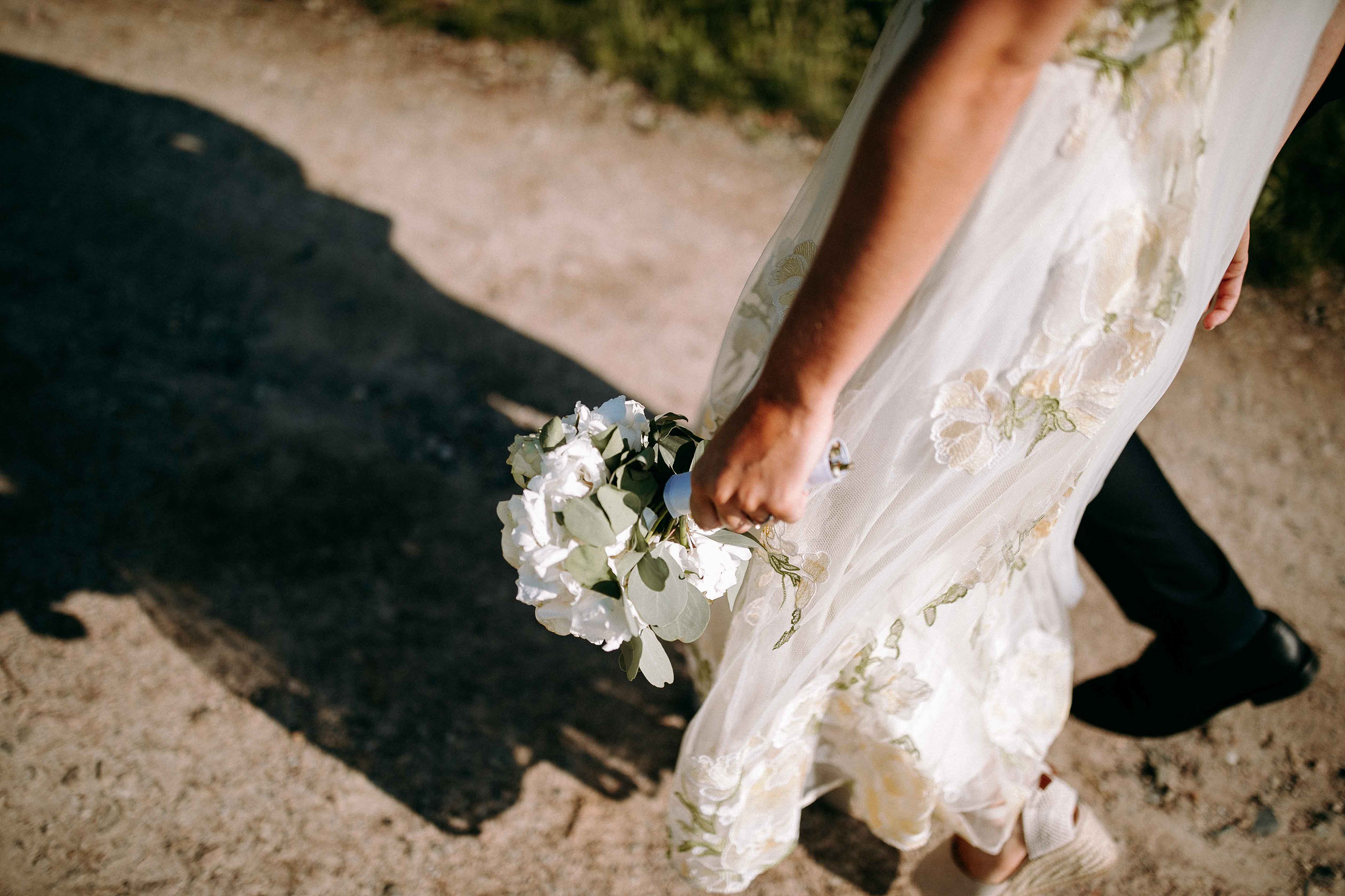 Weiße Hochzeitsblumen im Brautstrauß vor hellem Kleid