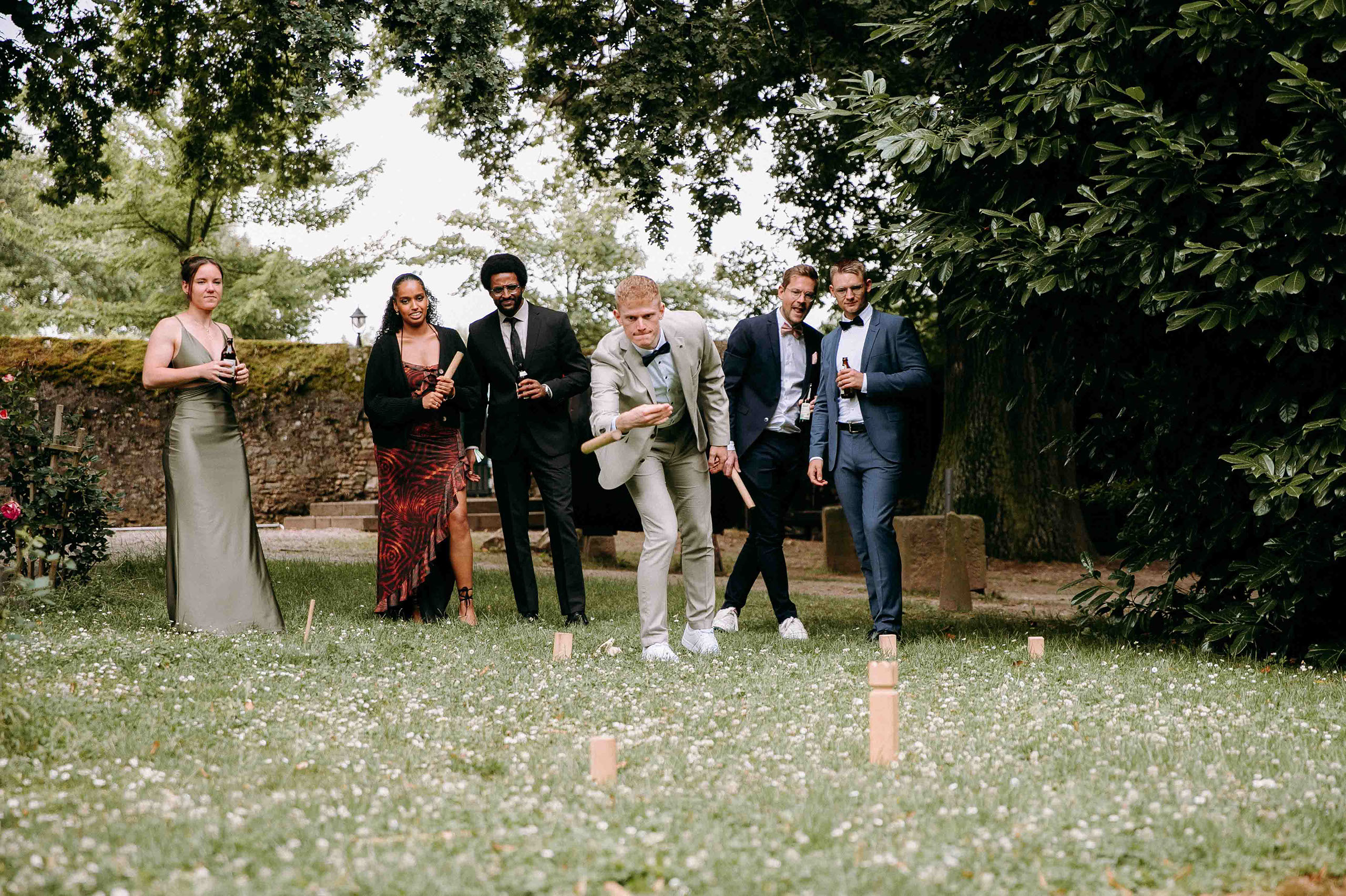 Gäste spielen Wurfspiel im Park der Hochzeitslocation Baron Knyphausen – Hochzeitsfotograf Rheingau fängt fröhliche Momente ein.