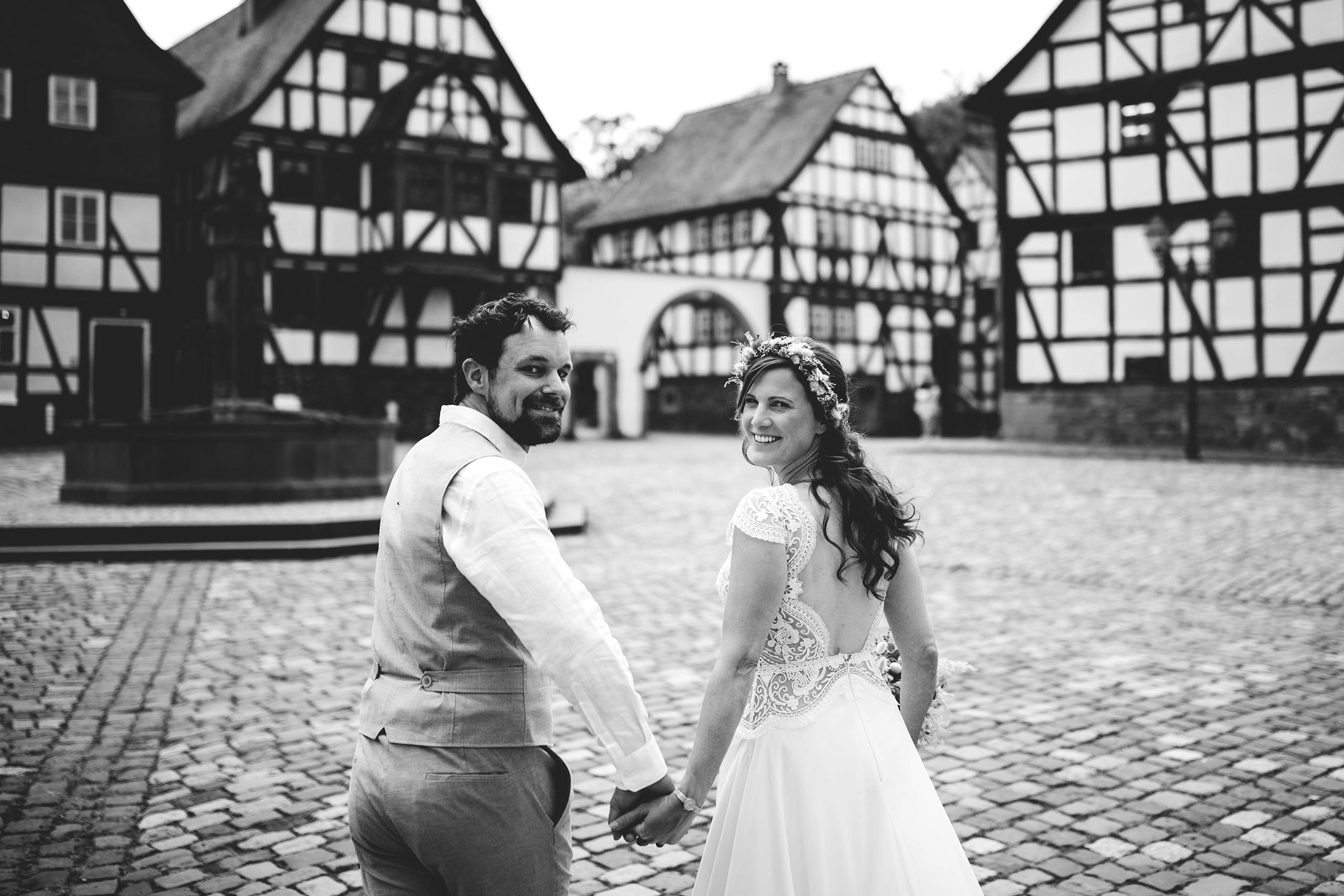 Brautpaar Hand in Hand zwischen Fachwerkhäusern im Freilichtmuseum Hessenpark – Hochzeitsfotos Bad Homburg