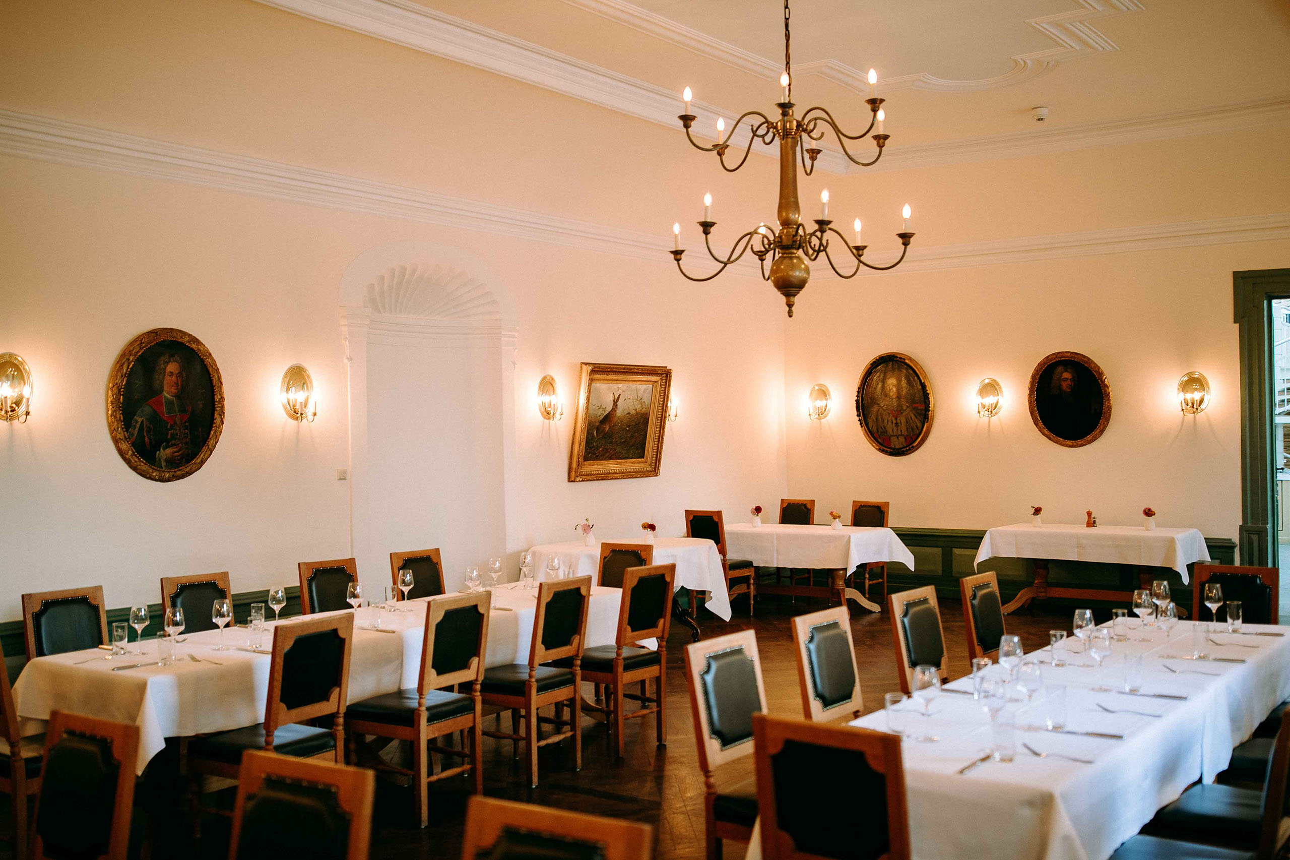 Tafeln mit weißen Tischdecken und Gemälden im Saal