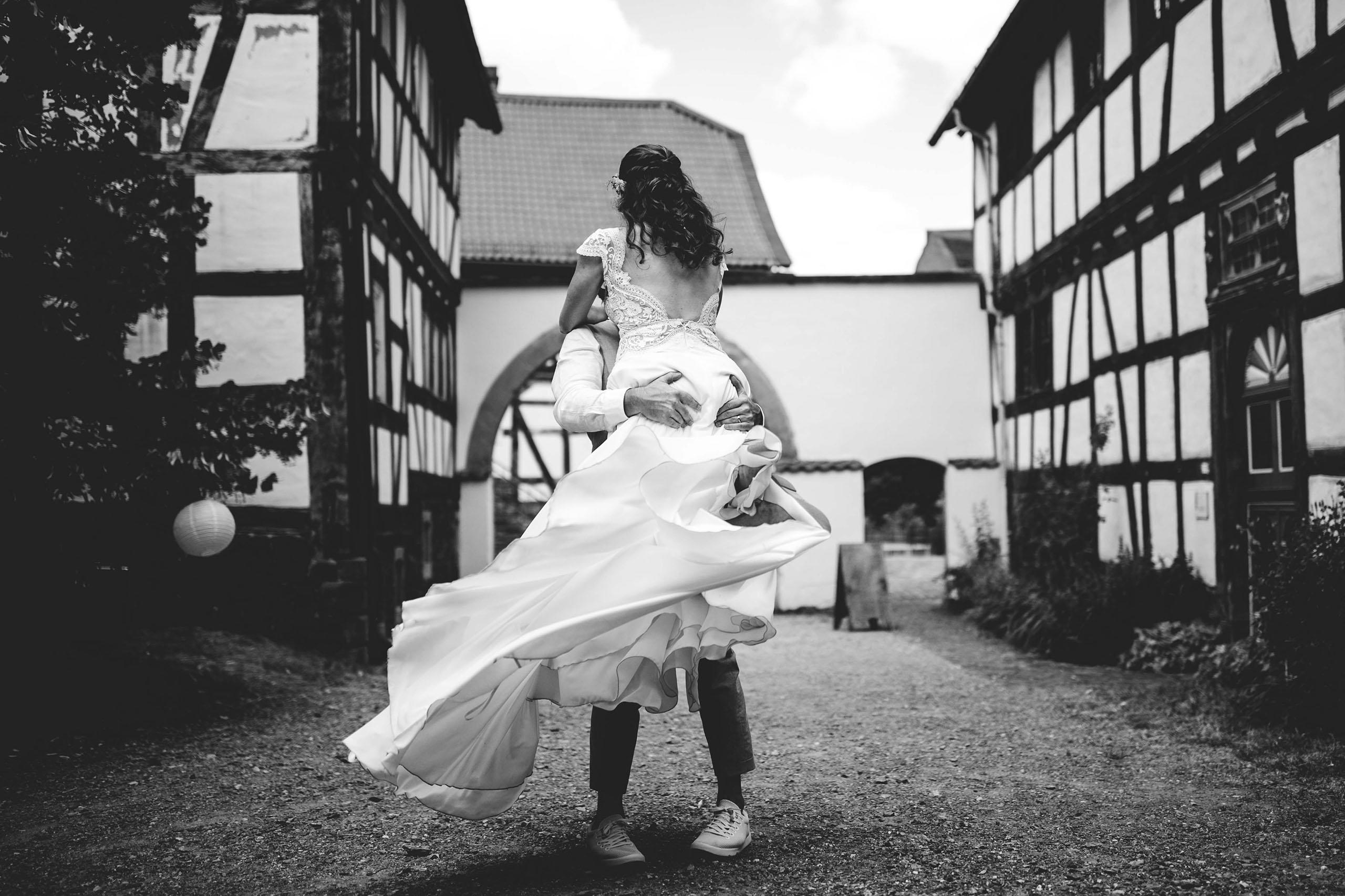 Bräutigam hebt die Braut in einer liebevollen Geste im Freilichtmuseum Hessenpark – Hochzeitsfotograf Bad Homburg