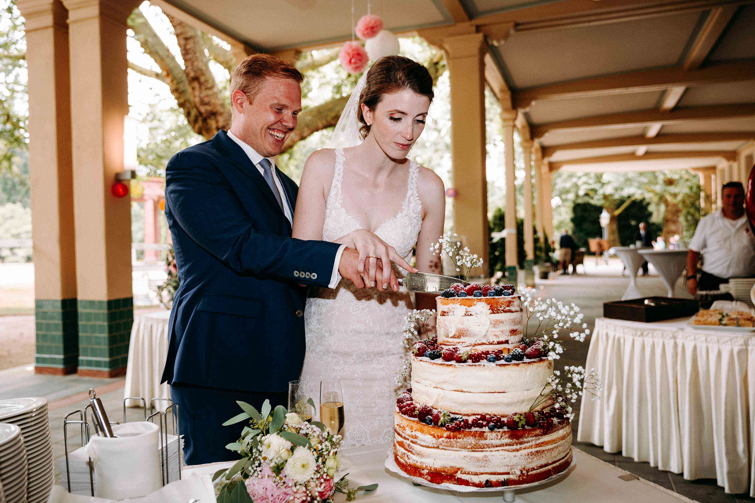 Brautpaar schneidet gemeinsam die Hochzeitstorte in der Orangerie im Kurpark Bad Homburg an.