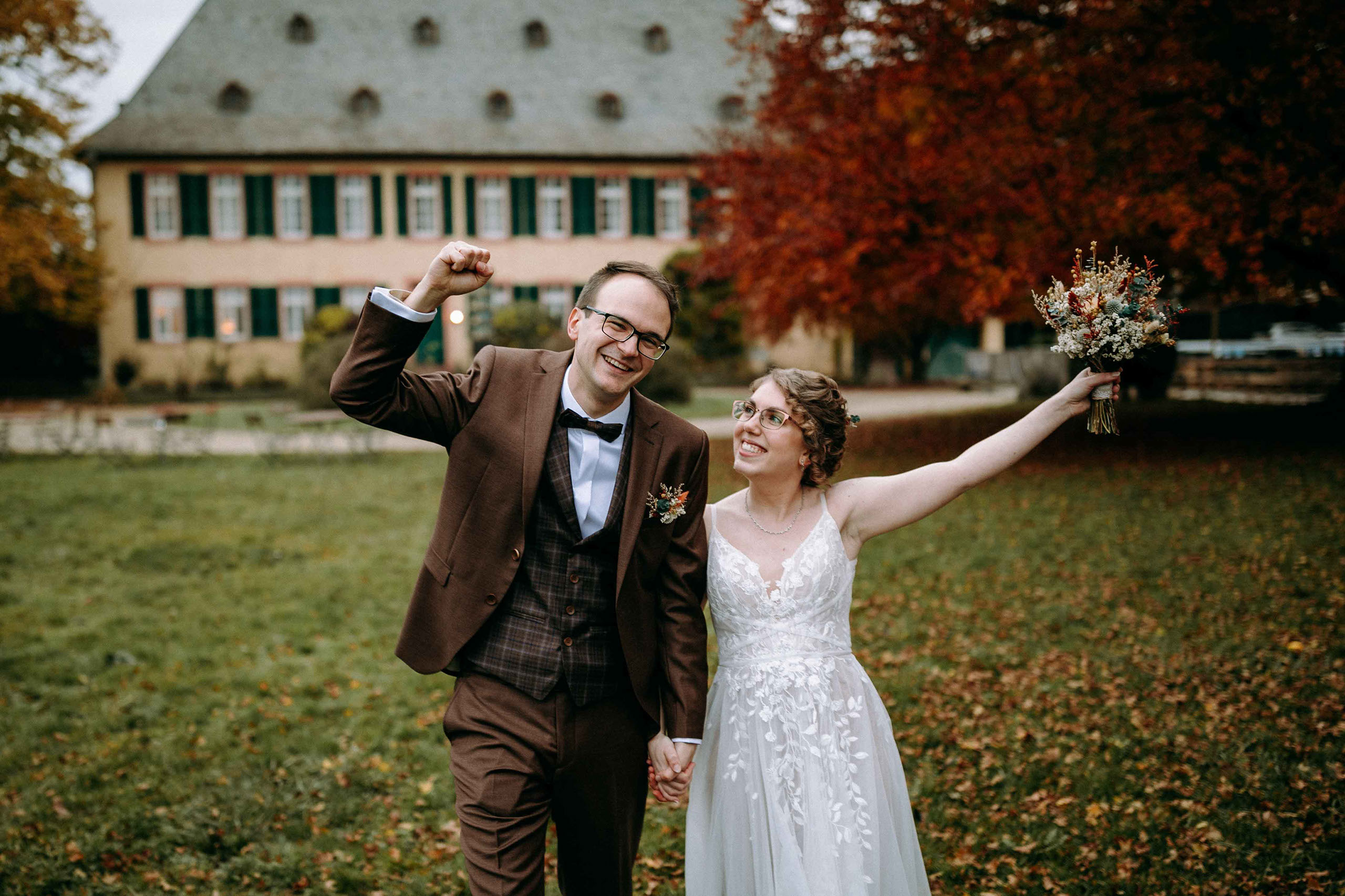 Das glückliche Brautpaar jubelt nach der Trauung vor dem Draiser Hof – Hochzeitslocation Baron Knyphausen im Rheingau.