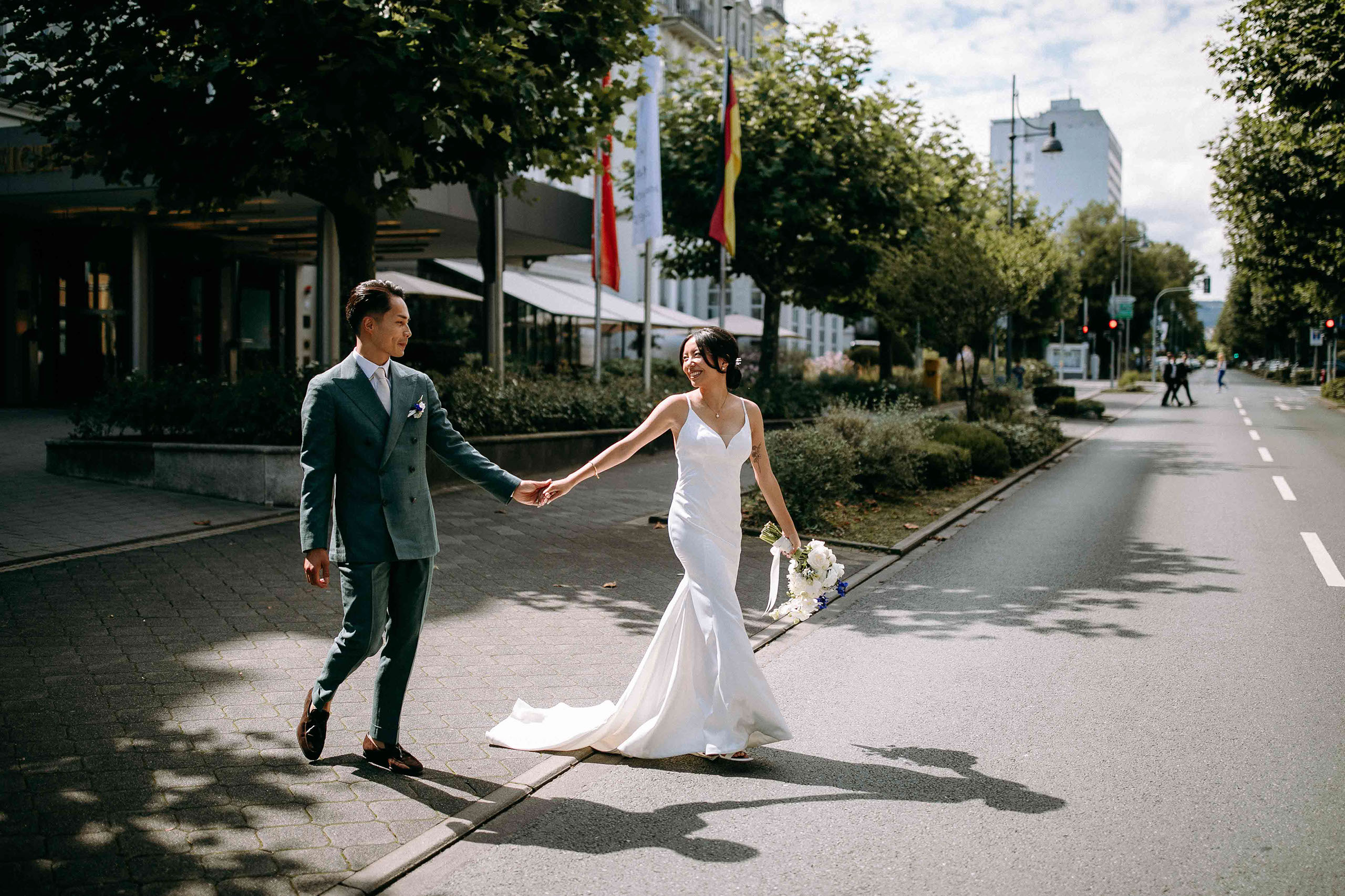 Brautpaar läuft gemeinsam über die Straße vor dem Hotel