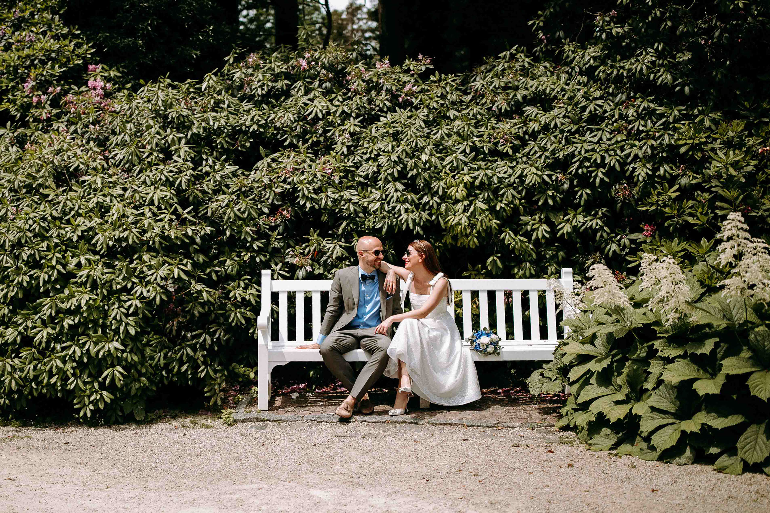 Fröhliches Brautpaar auf Parkbank – Hochzeitsfotos im Schlossgarten des Schlosshotel Kronberg