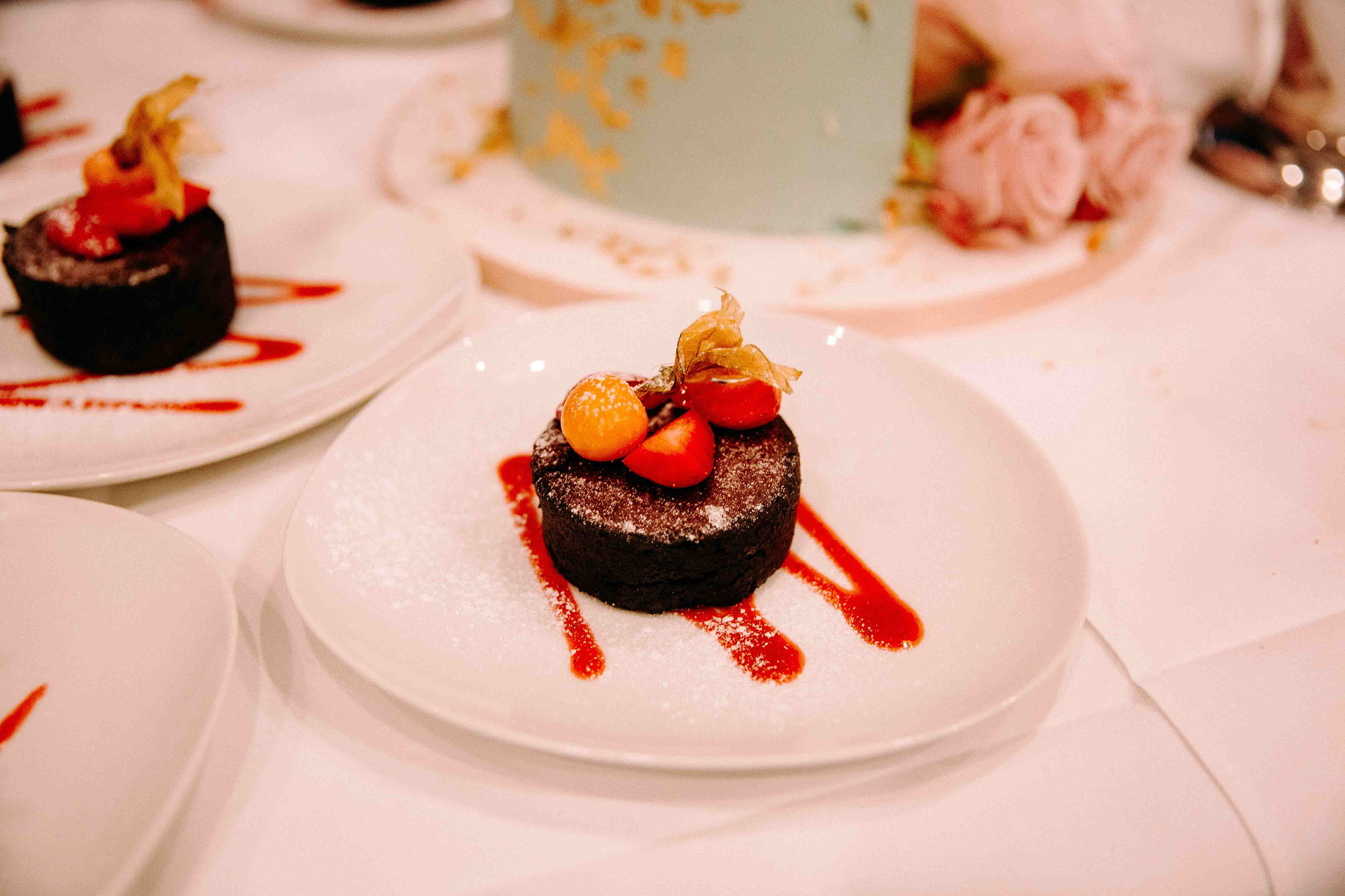 Dessert aus Schokoladenkuchen mit Erdbeeren und Physalis auf weißem Teller – Hochzeitslocation Am Niederwald im Rheingau.