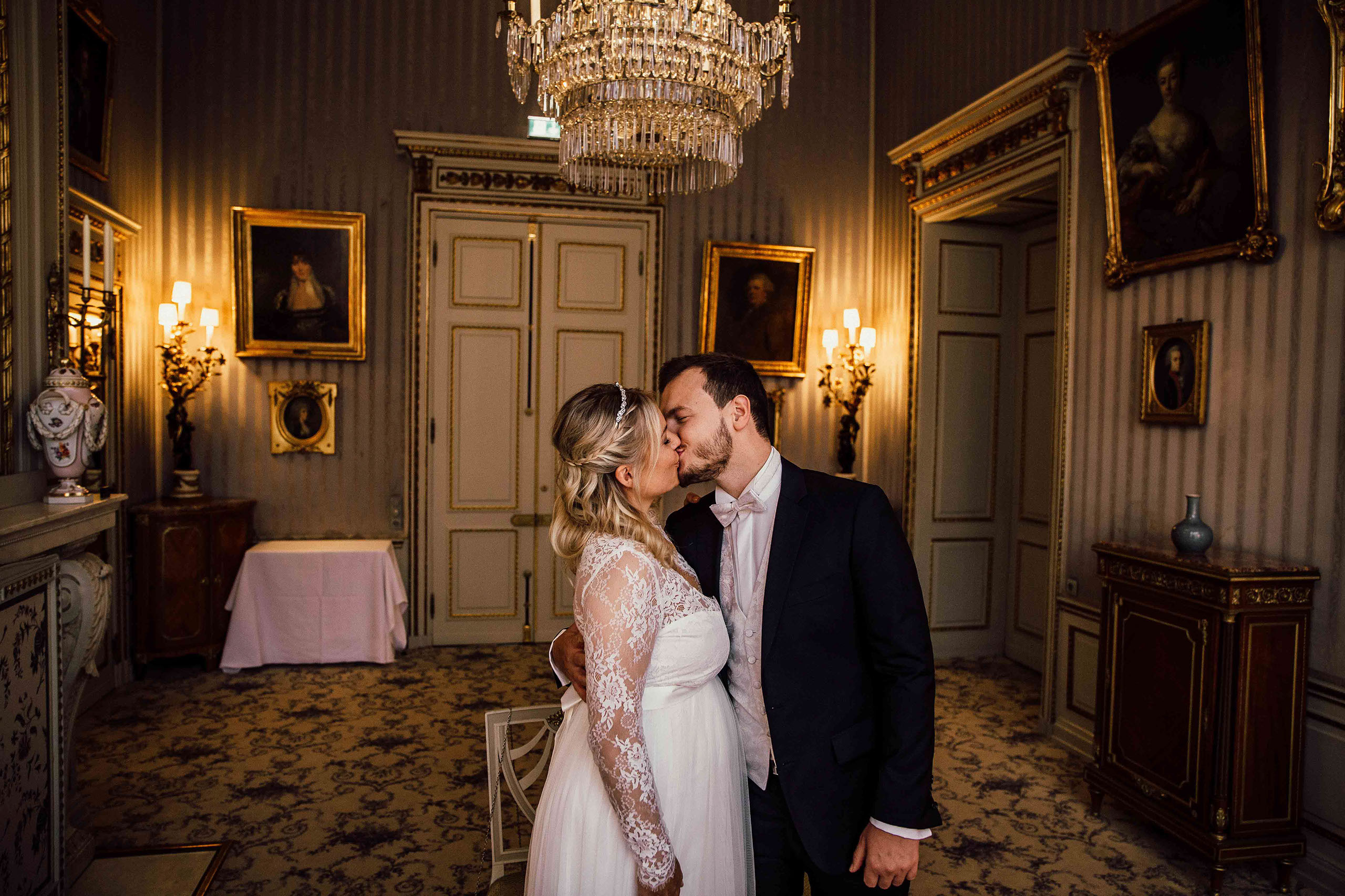 Kuss des Brautpaares unter Kronleuchter – Hochzeitsfoto im Schlosshotel Kronberg