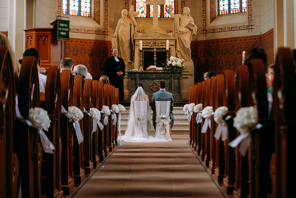 Das Brautpaar sieht sich verliebt im Kaiserdom am Altar an.