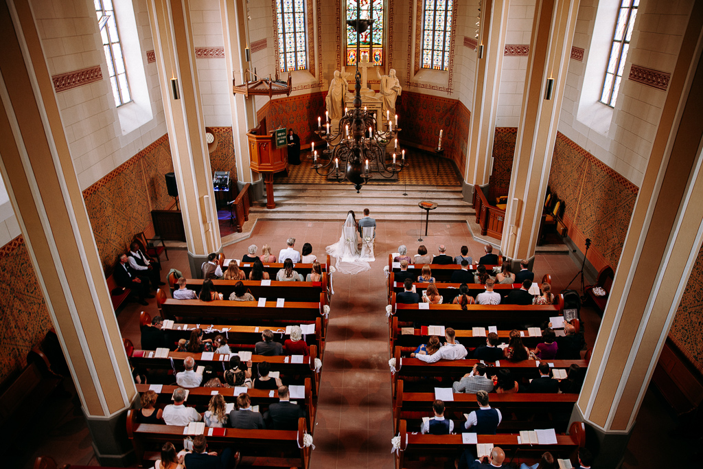 Das Brautpaar sieht sich verliebt im Kaiserdom am Altar an.