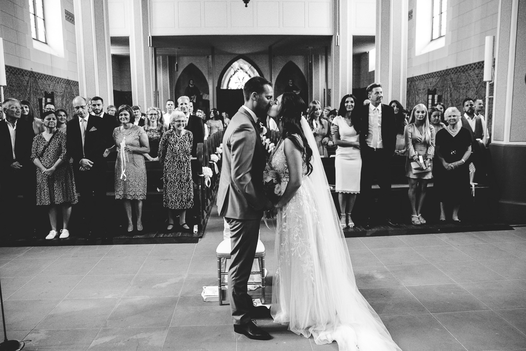 Das Brautpaar sieht sich verliebt im Kaiserdom am Altar an.