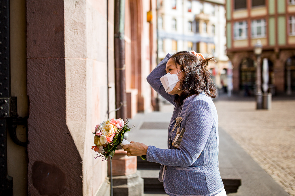 Die Braut hat eine Maske auf und betritt das Standesamt Römer in Frankfurt am Main. Der Hochzeitsfotograf aus Frankfurt hält den Moment fest.